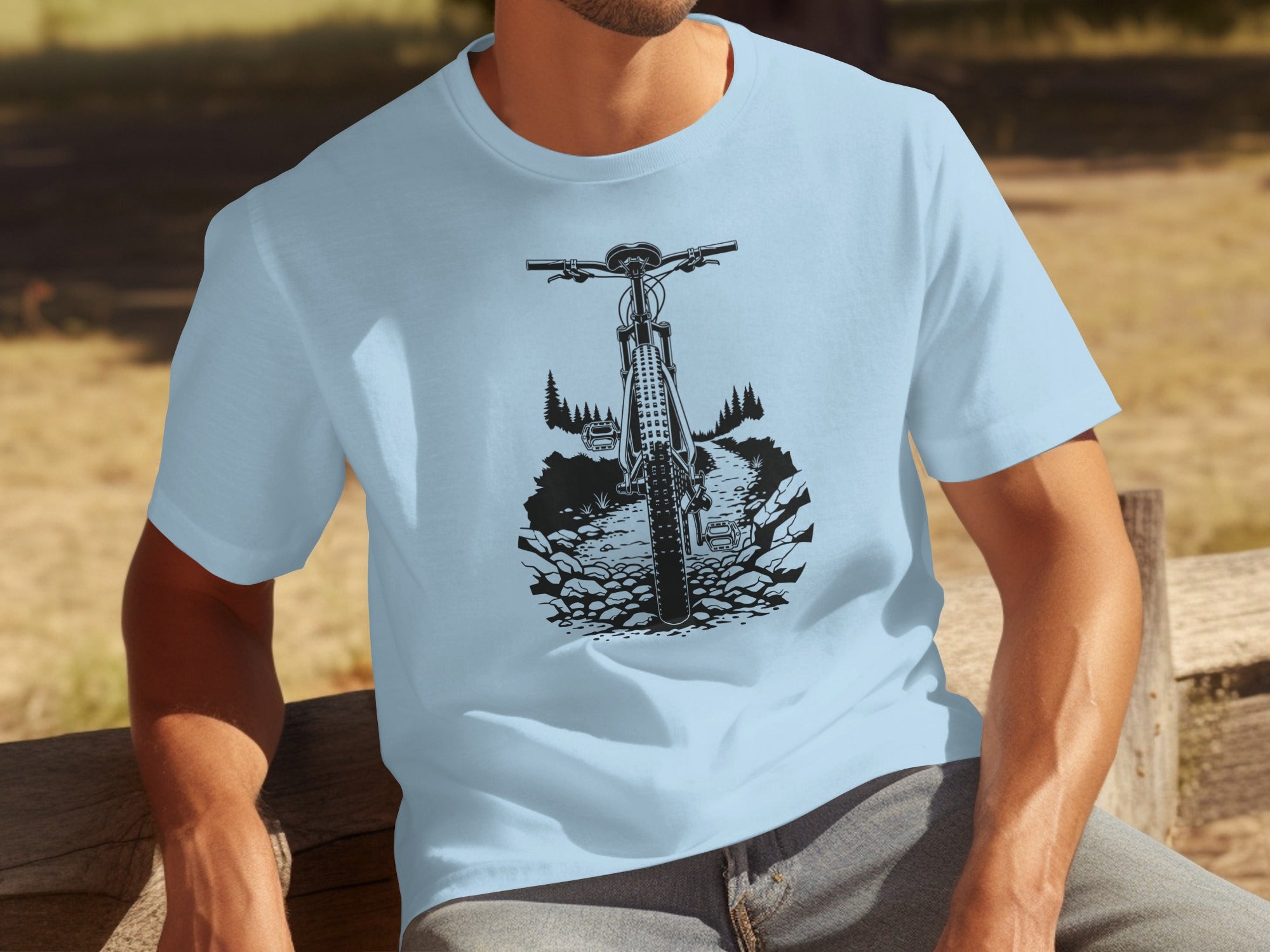 Light blue t-shirt with a black line drawing of a front-facing mountain bike on a rocky path.