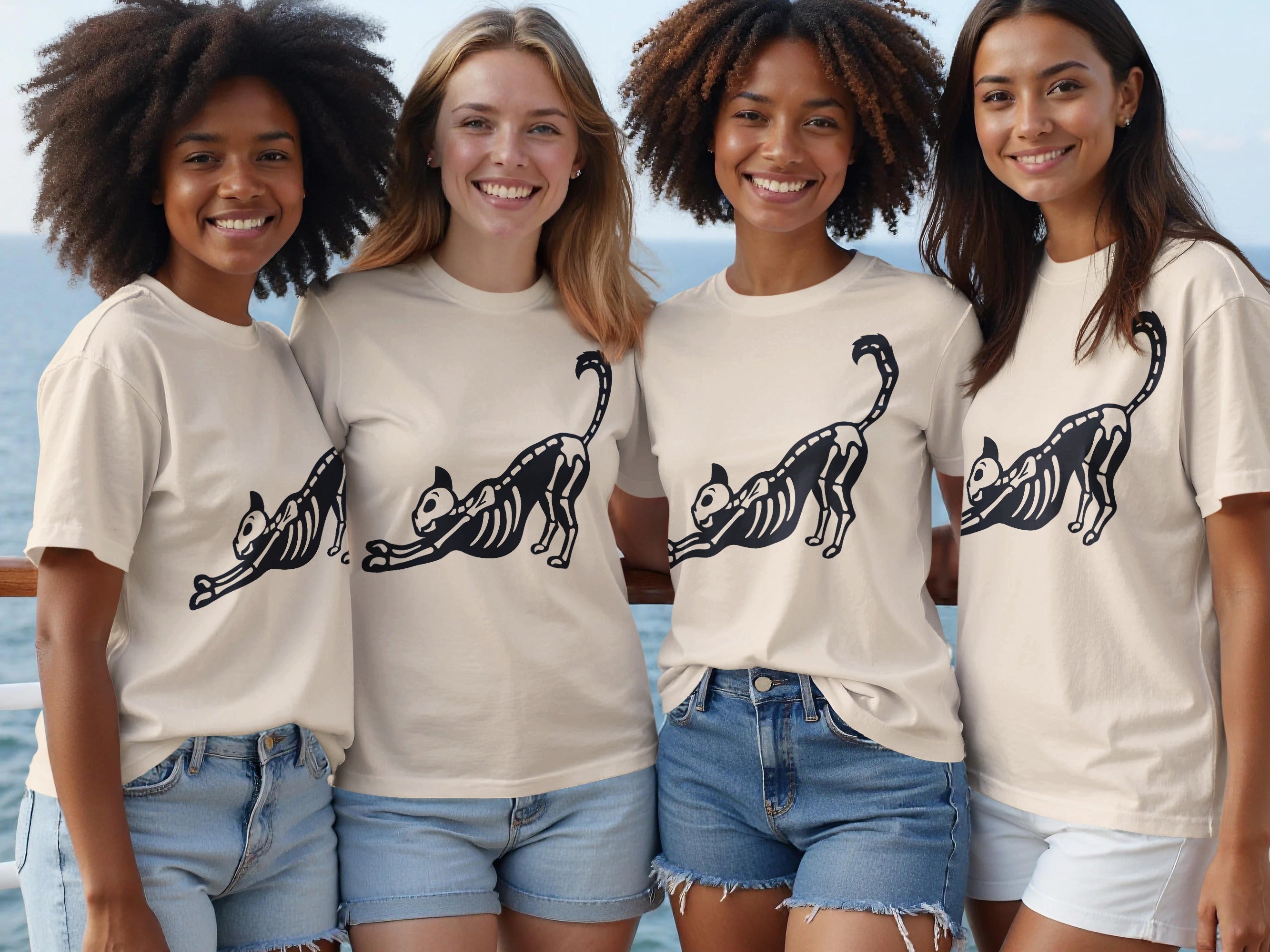 Four women wear cream t-shirts featuring a black skeleton cat graphic design.