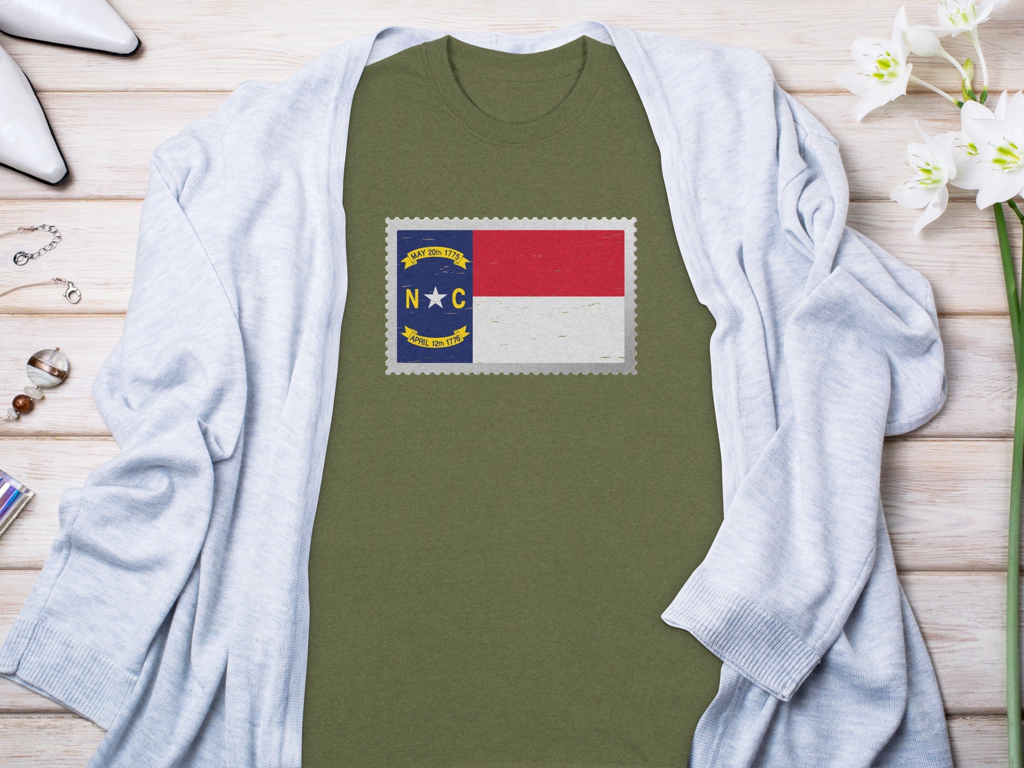 T-shirt with North Carolina flag postage stamp graphic, next to a light blue cardigan.