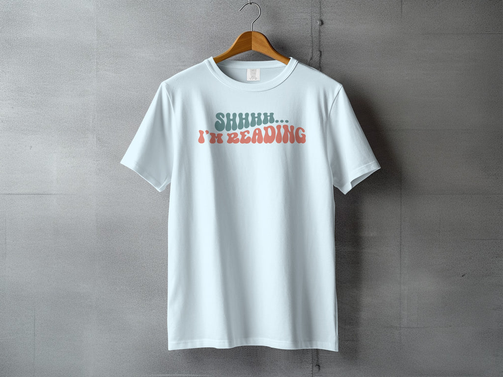 Light blue t-shirt with "SHHHH... I'M READING" text in retro font.