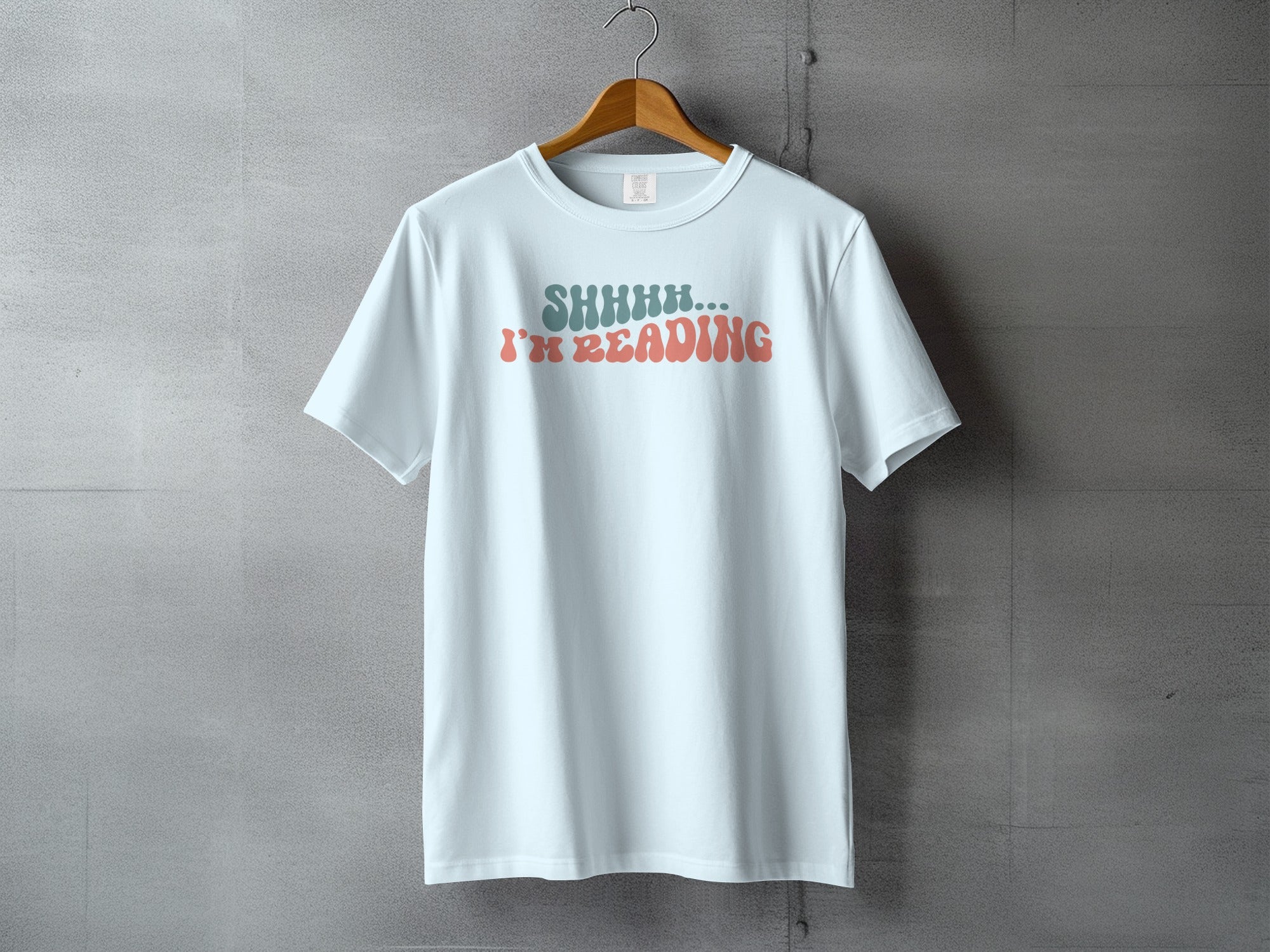 Light blue t-shirt with "SHHHH... I'M READING" text in retro font.