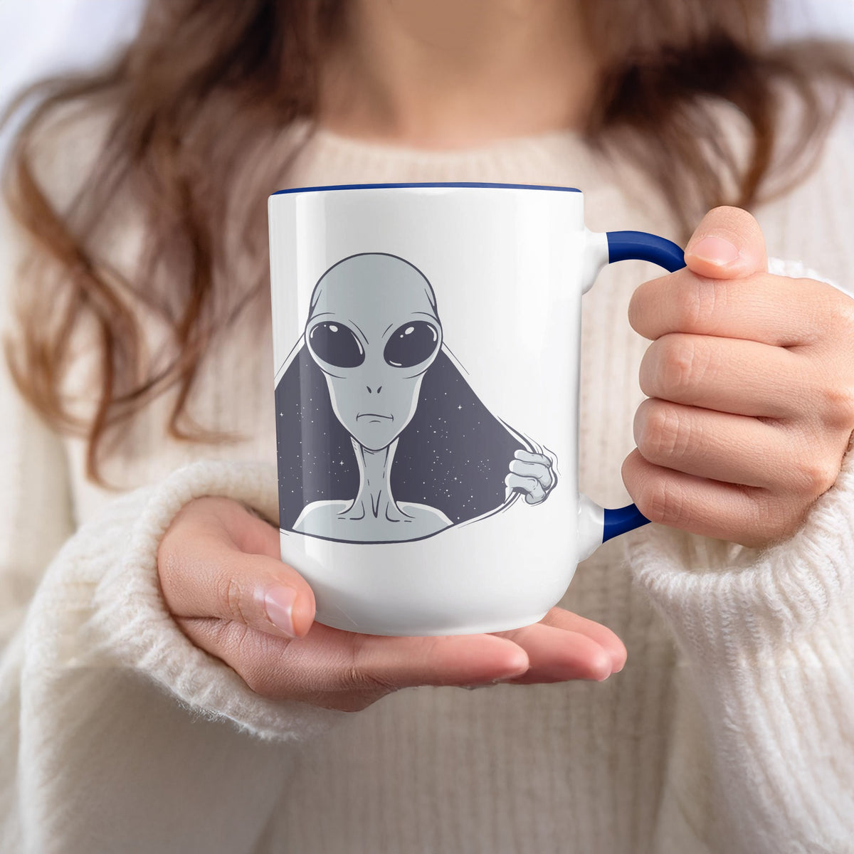White mug with blue trim featuring an alien peeking through a starry background.