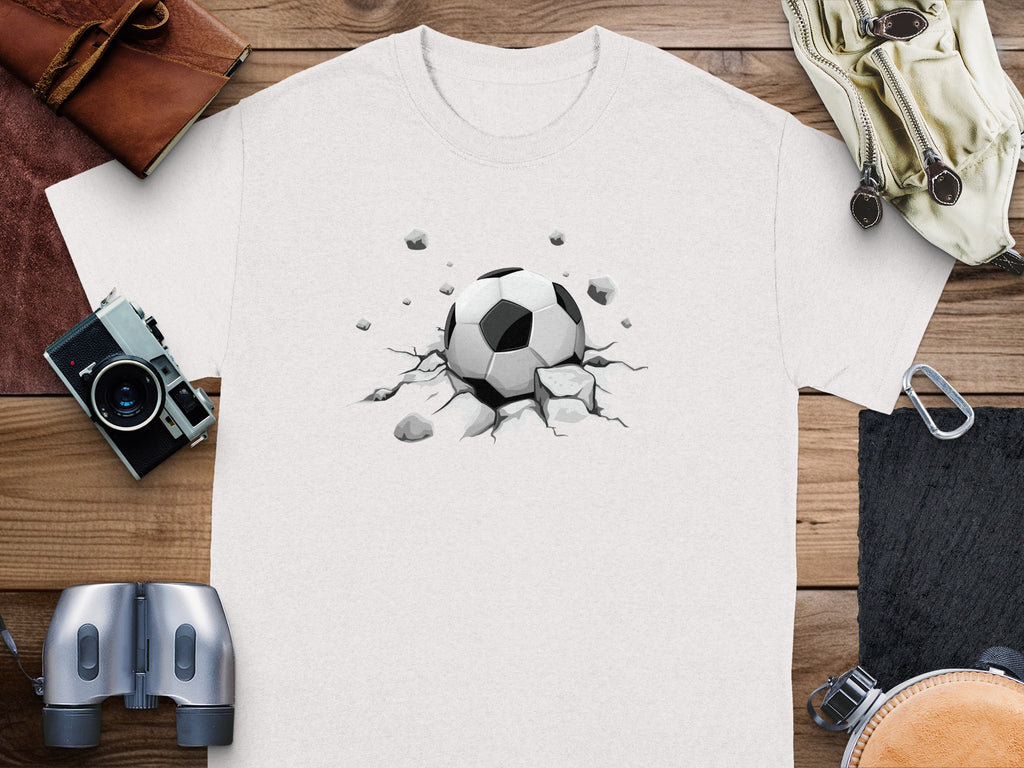 White t-shirt with graphic of a soccer ball breaking through the ground.