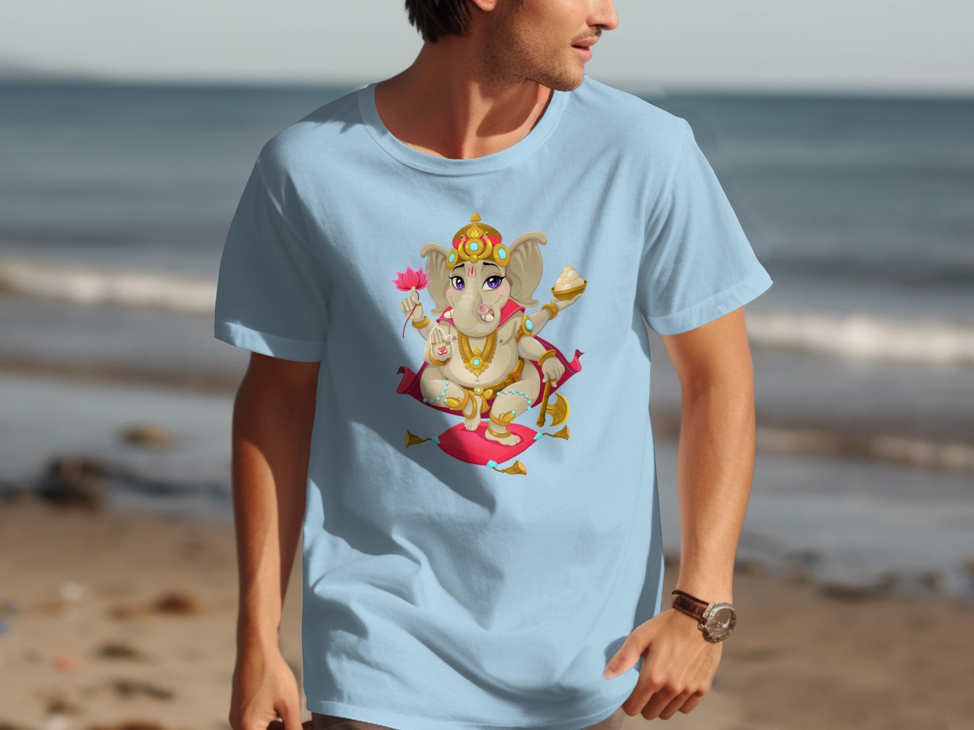 Light blue t-shirt with a cartoon Ganesha illustration holding a lotus flower and sweets.