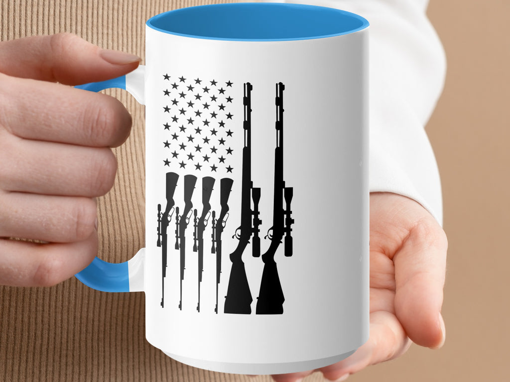 White mug with blue rim, featuring silhouette of American flag with rifles.