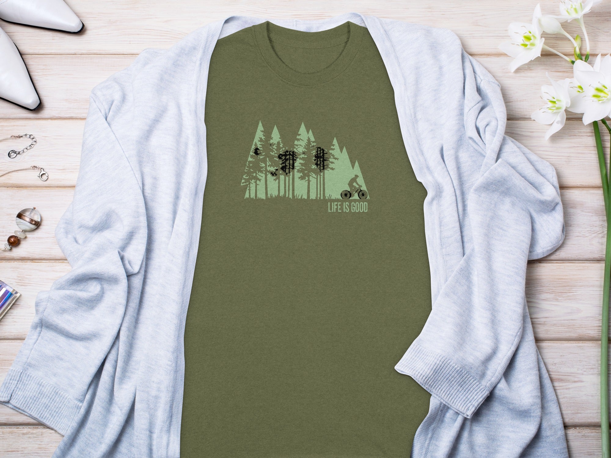 Olive green t-shirt with trees, mountains, and a cyclist graphic; "LIFE IS GOOD".
