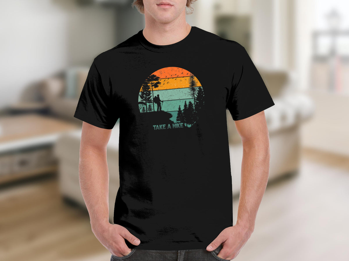 Black t-shirt with "TAKE A HIKE" text over a vintage sunset scene.