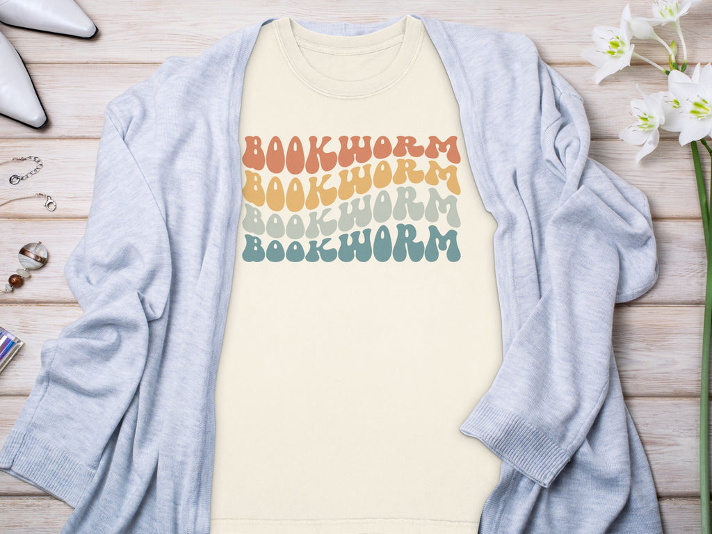 Cream t-shirt with retro "BOOKWORM" text in four wavy pastel rows.