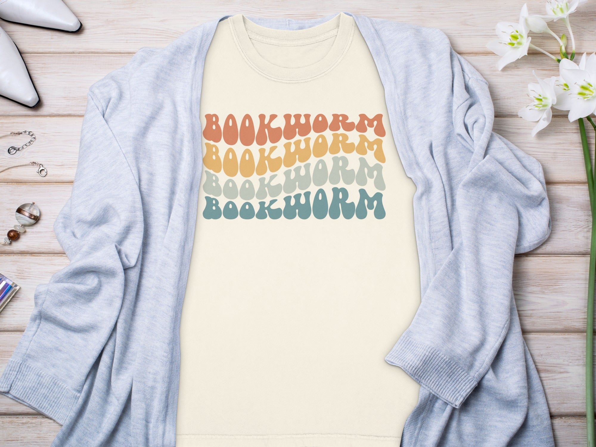 Cream t-shirt with retro "BOOKWORM" text in four wavy pastel rows.