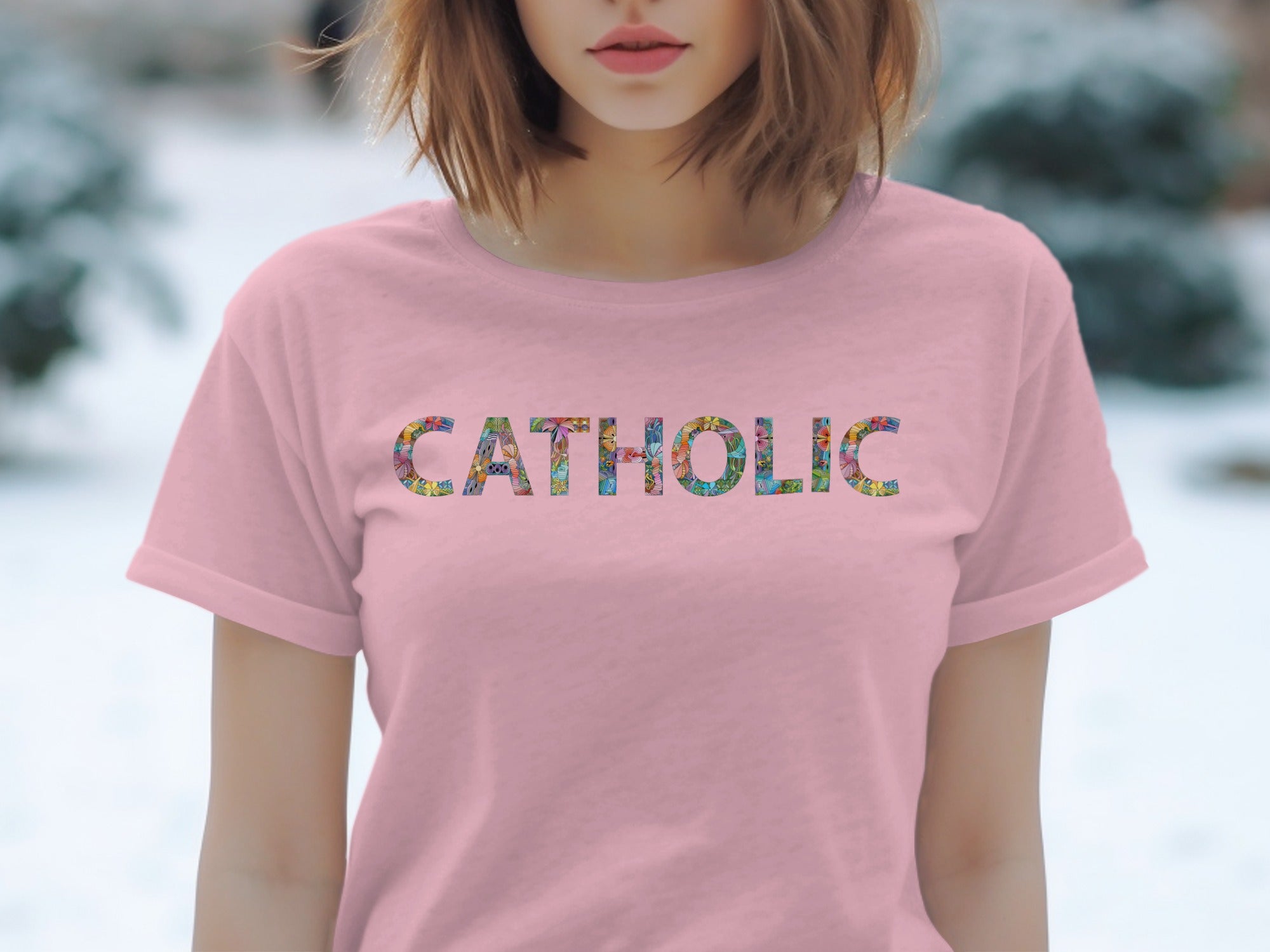 Pink t-shirt with "CATHOLIC" printed in colorful, intricate floral patterns.