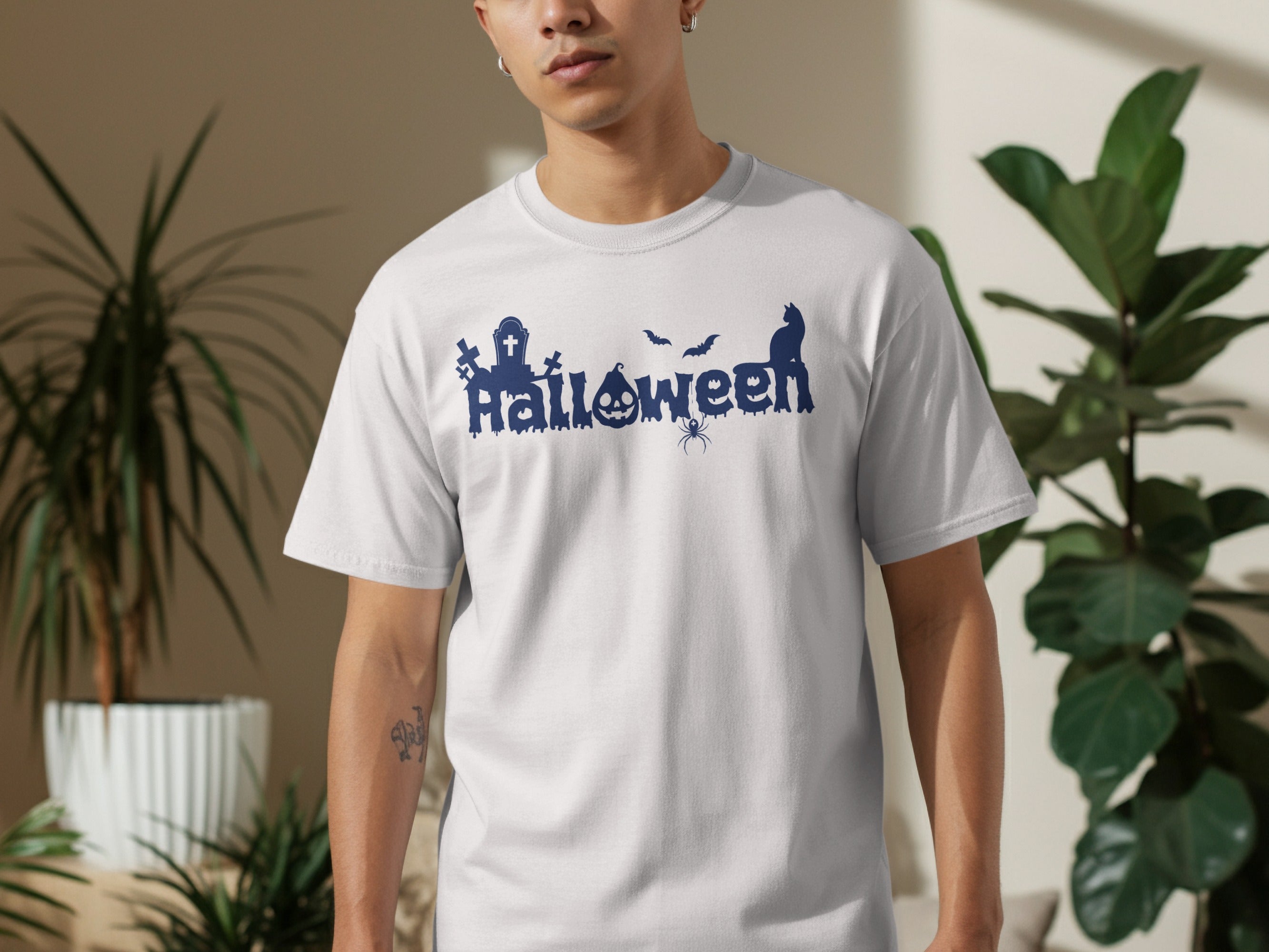 White t-shirt with blue Halloween graphic featuring spider, bats, cat, tombstones, and pumpkin.