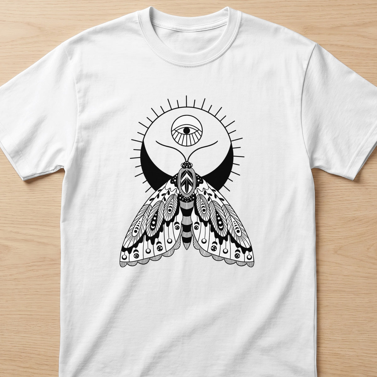 White t-shirt with a black line drawing of a moth with an eye above a crescent moon.
