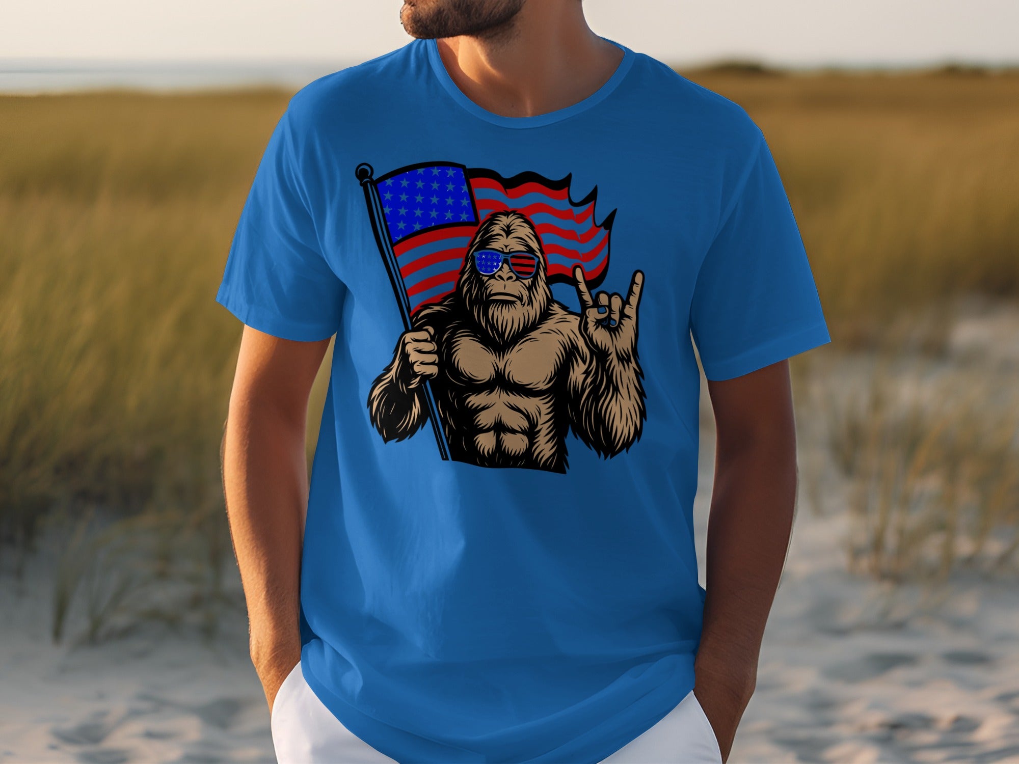 Bigfoot wearing sunglasses holds American flag and makes rock and roll hand gesture.