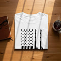 White t-shirt with black American flag stars and gun silhouettes design.