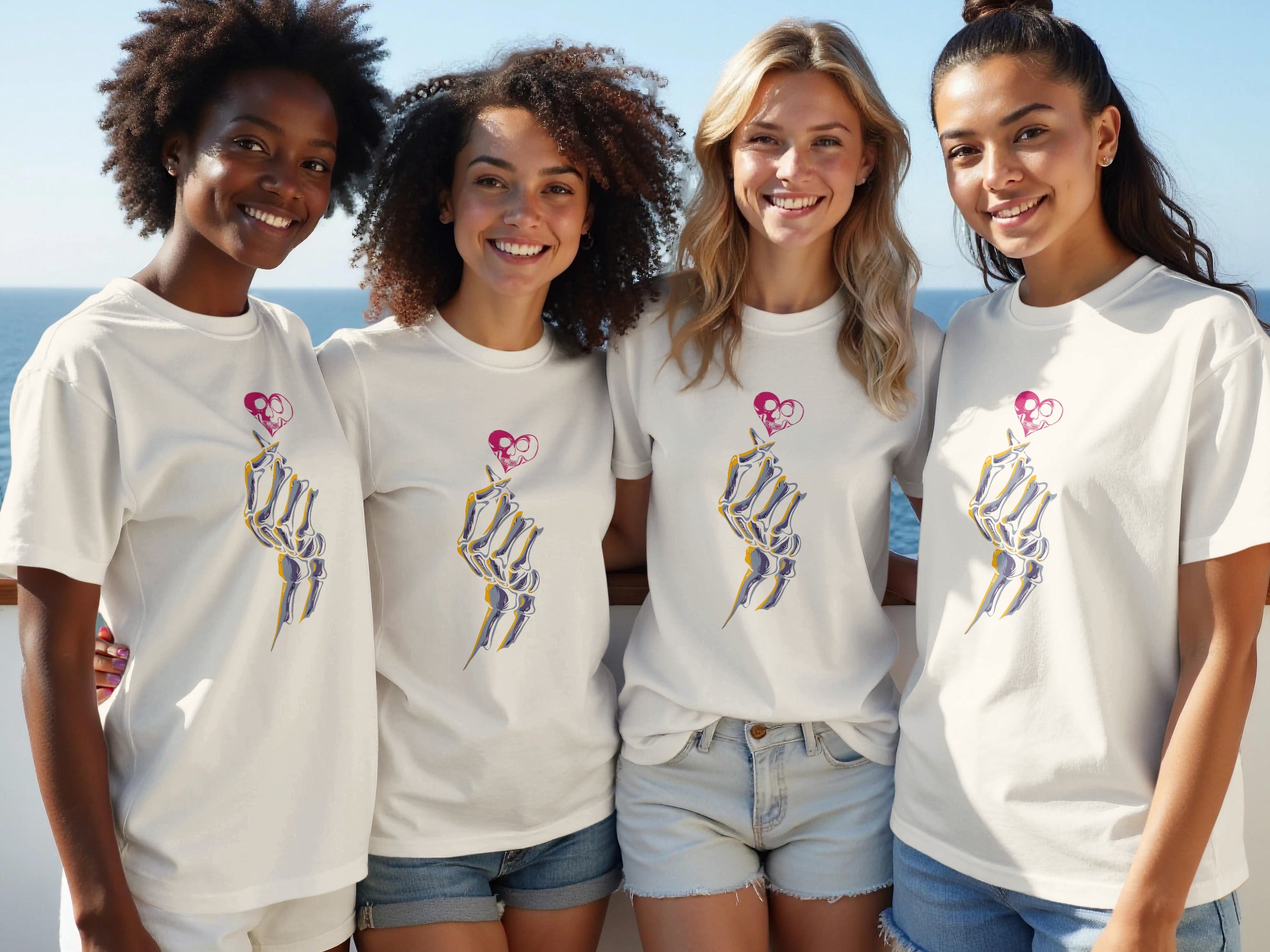 Four smiling women in white t-shirts with skeleton hand heart graphic.