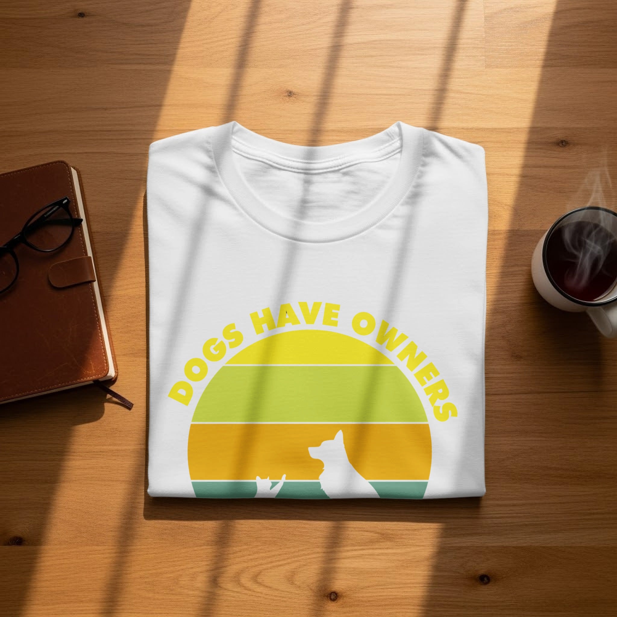 White t-shirt with yellow text "Dogs Have Owners" and dog and cat silhouettes.