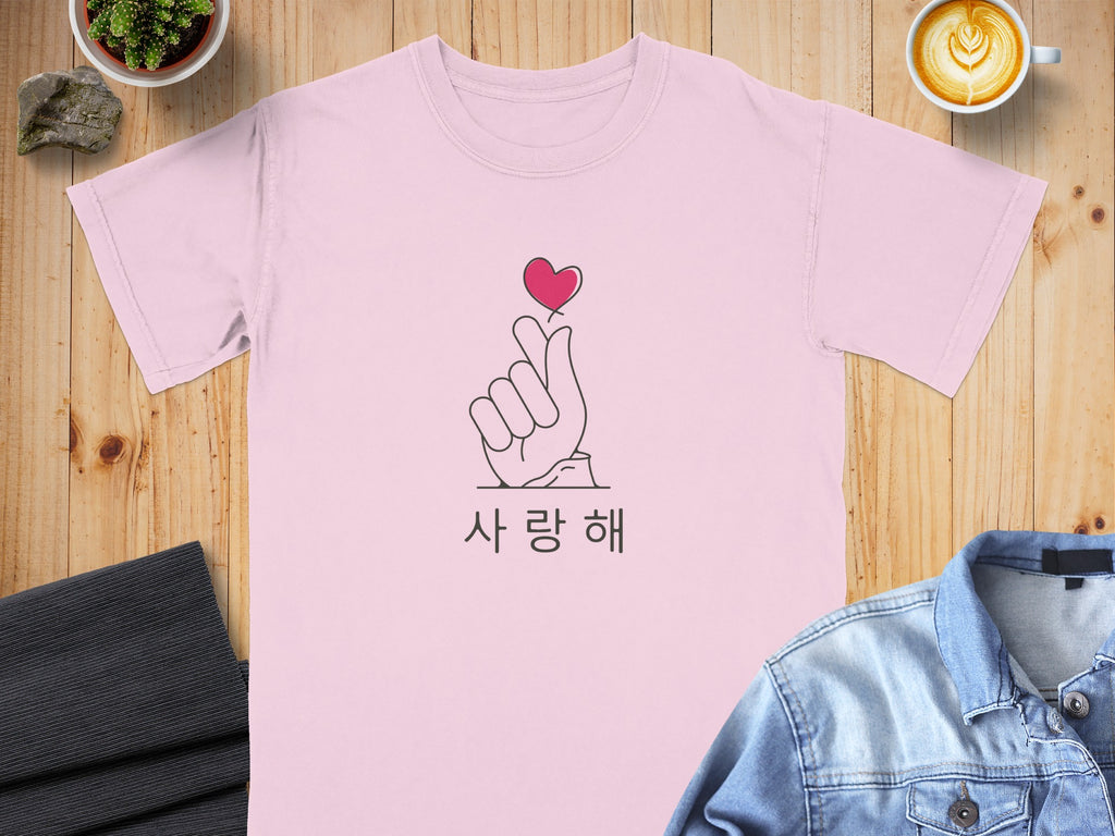 Pink t-shirt with a hand making a heart gesture and Korean text.