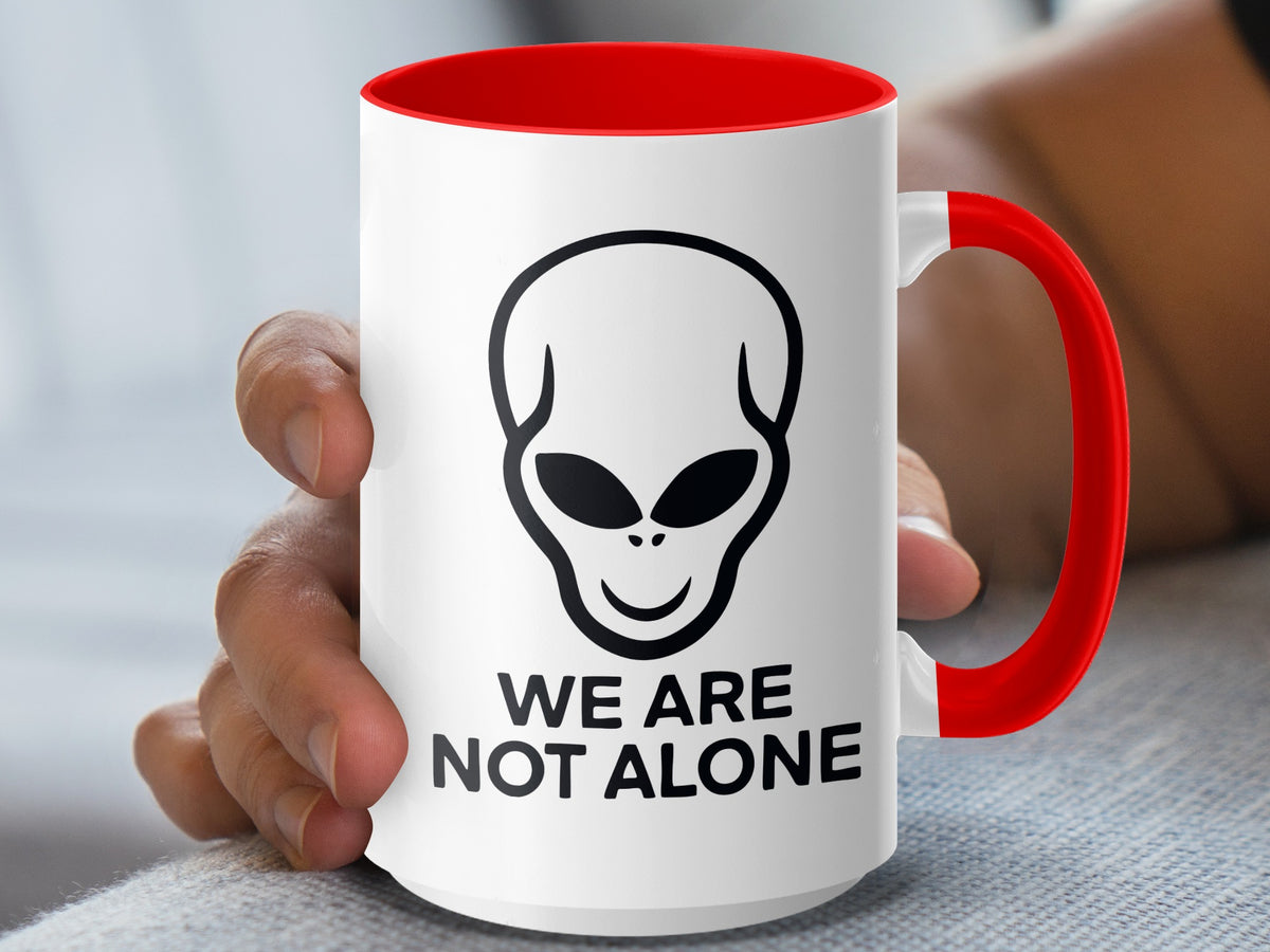 White mug with red handle and rim, featuring an alien head and "WE ARE NOT ALONE" text.