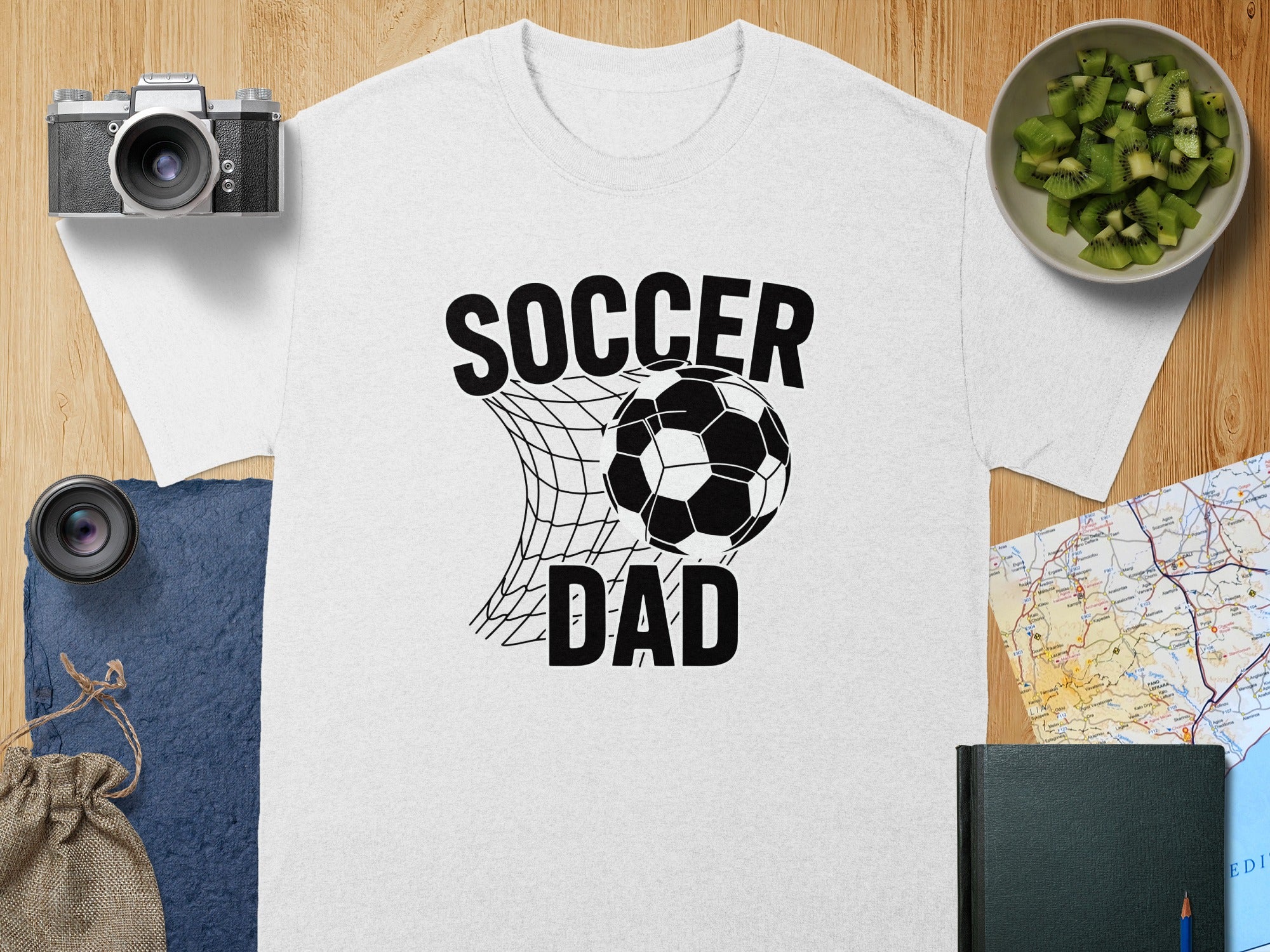 White t-shirt with "SOCCER DAD" text and soccer ball in net graphic.