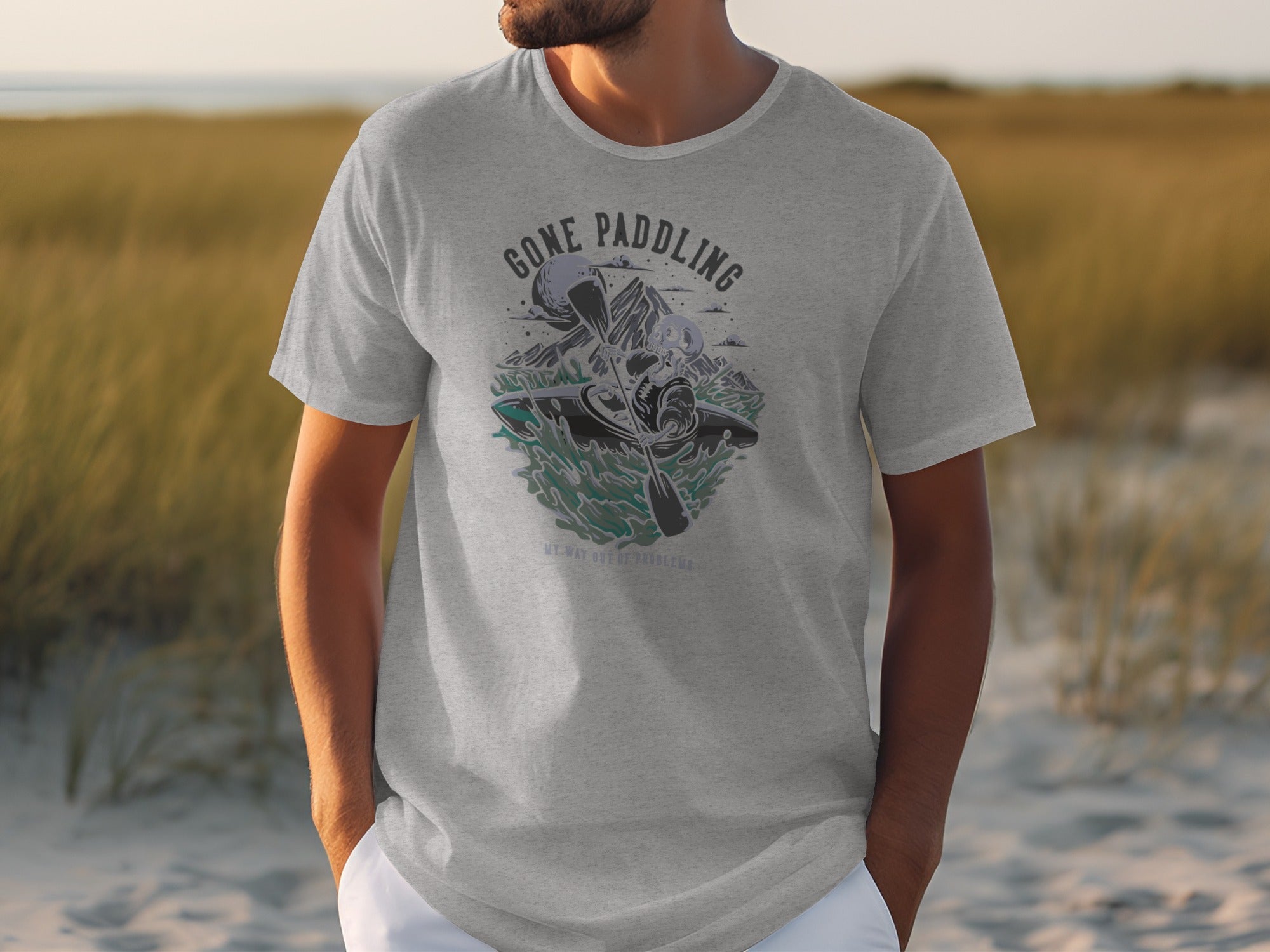 Grey t-shirt with a graphic of a skeleton kayaking and the text "Gone Paddling".