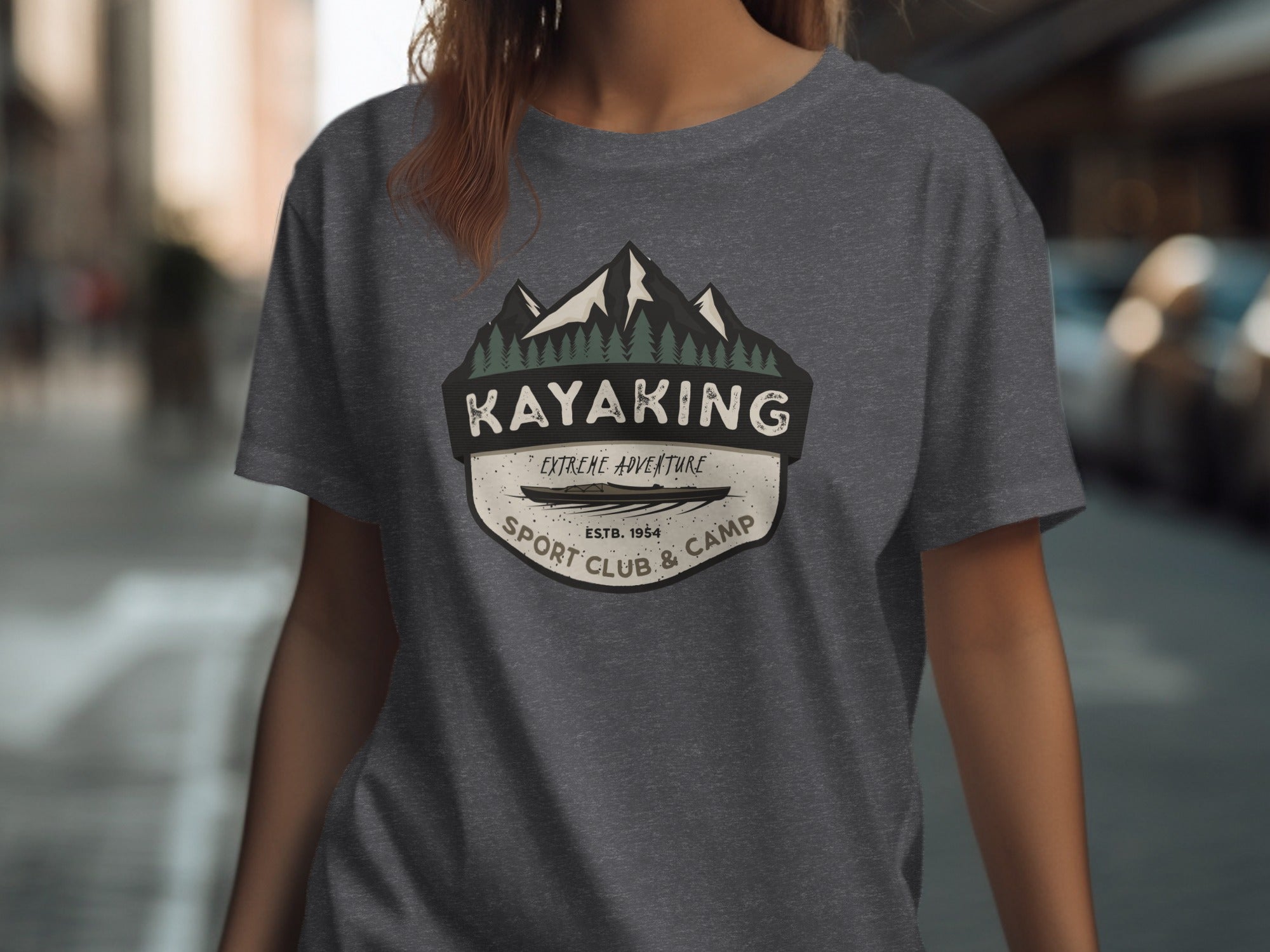 Gray t-shirt with a circular emblem featuring mountains, pine trees, a kayak, and text.