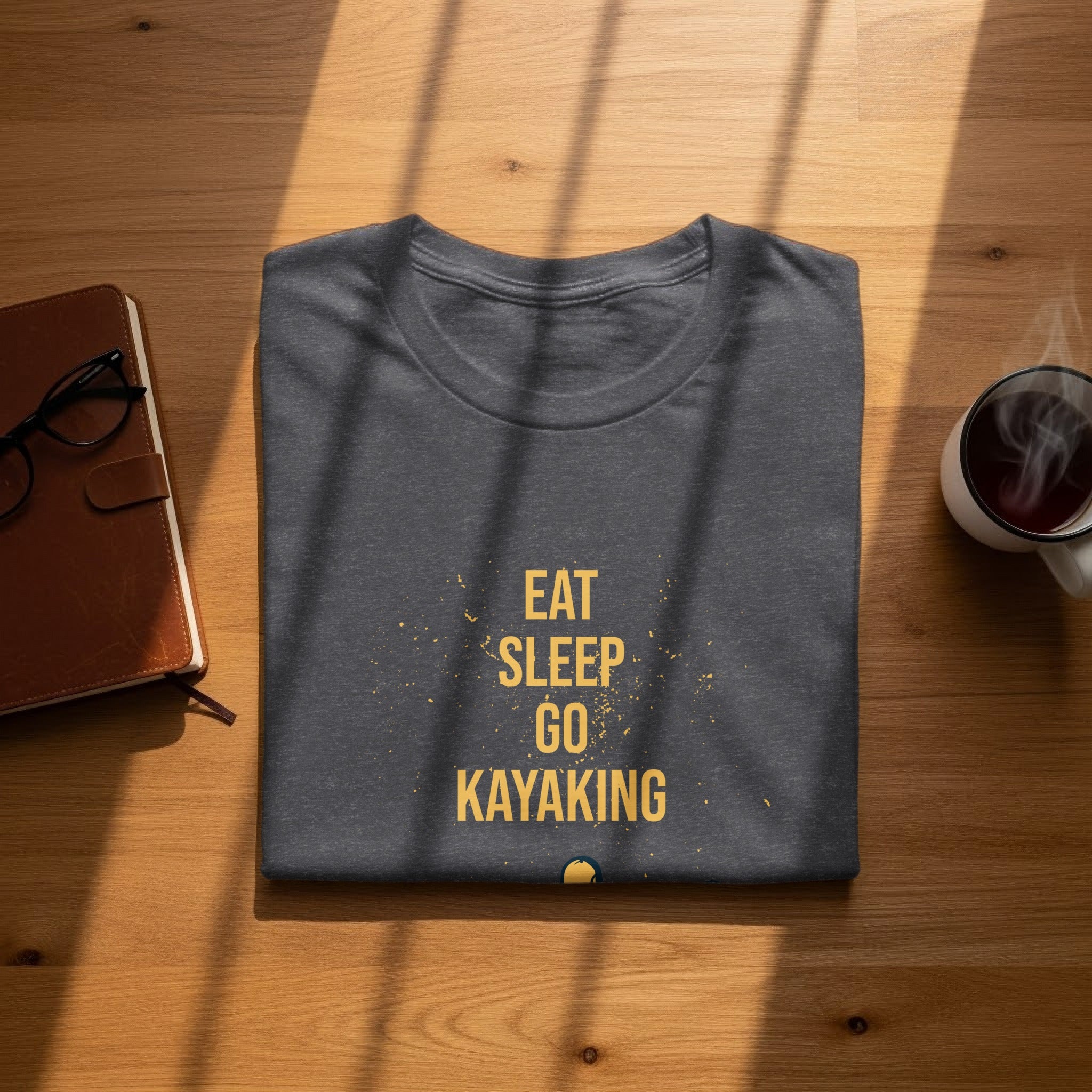Charcoal t-shirt with "Eat Sleep Go Kayaking" text on a wooden surface.
