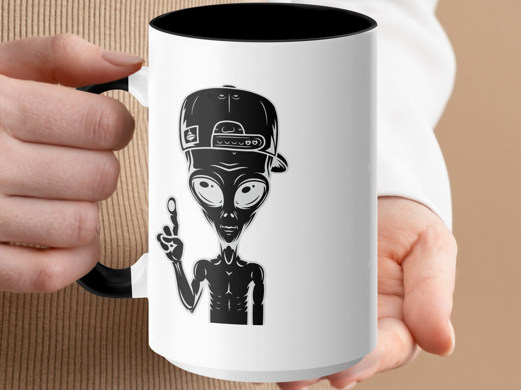 White mug with black interior features a black silhouette of an alien wearing a baseball cap.