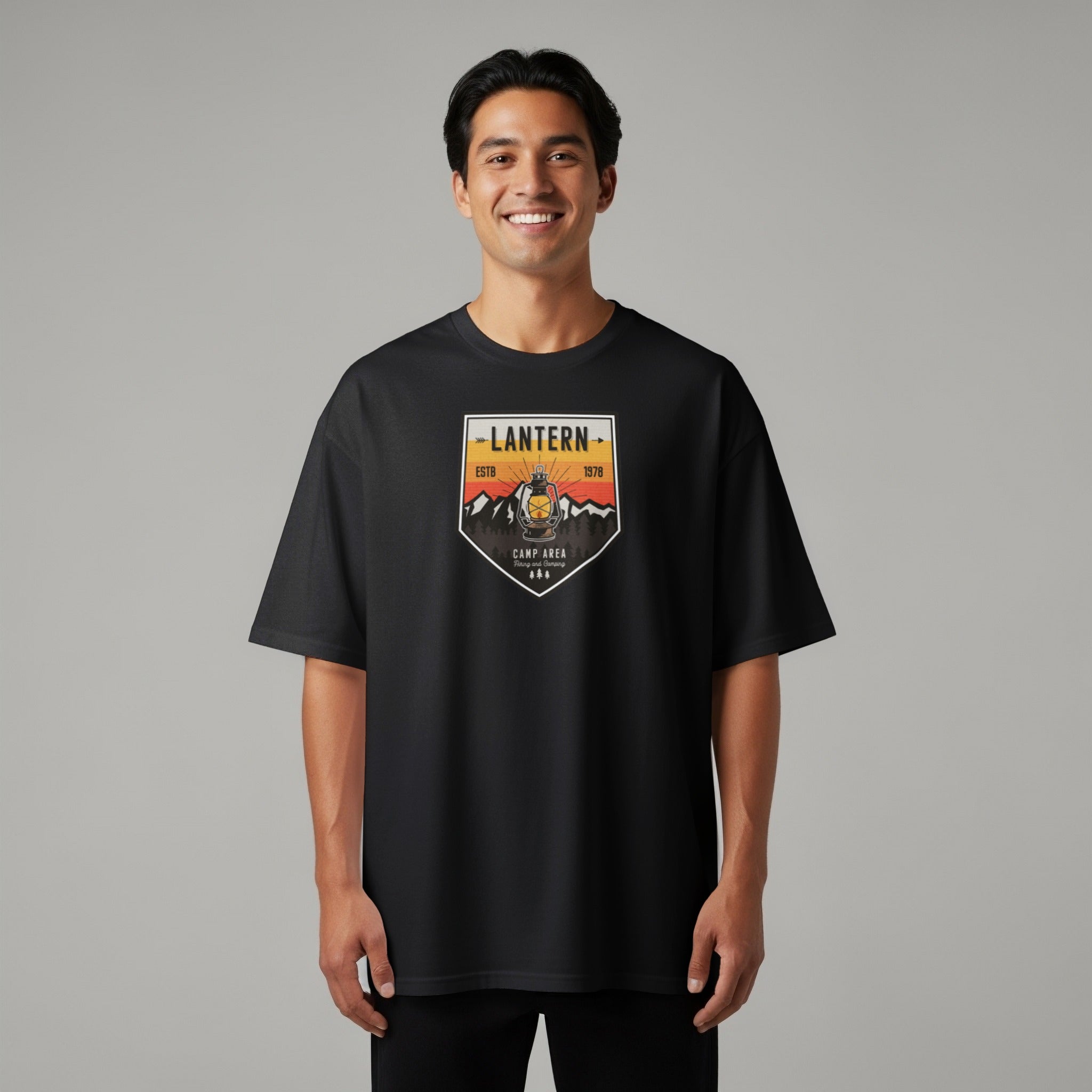 Black t-shirt with a badge graphic featuring a lantern, mountains, trees, and text.