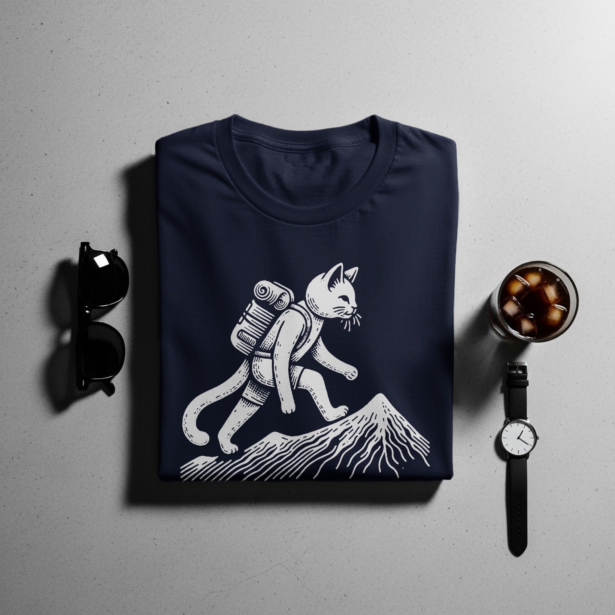 Navy t-shirt with white graphic of a cat hiking up a mountain.