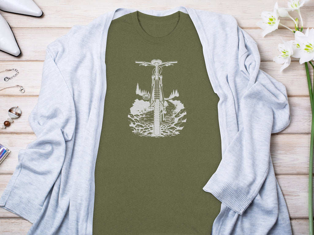 Green t-shirt with white bicycle graphic on a rocky trail with trees.