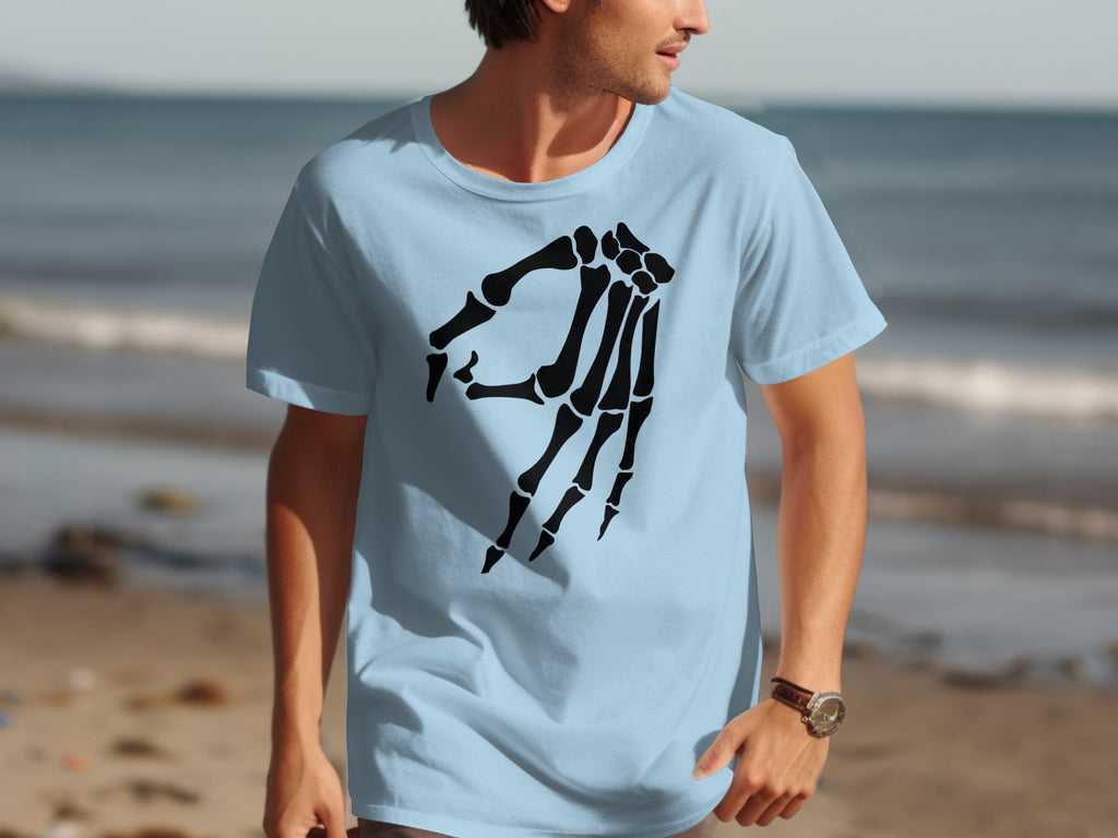 Light blue t-shirt with black skeleton hand graphic on beach background.