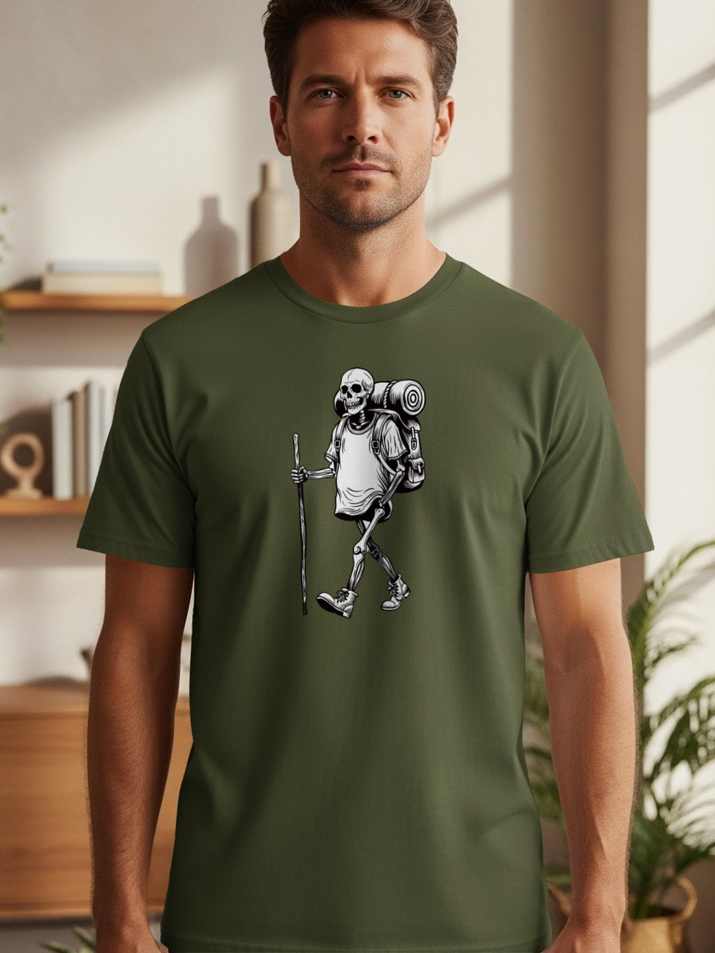Skeleton hiker with backpack and walking stick graphic on a green t-shirt.