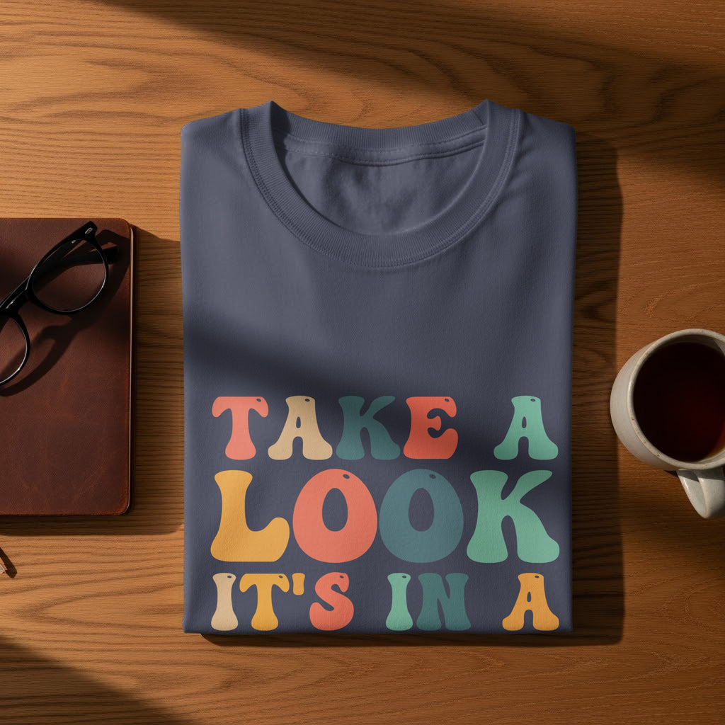 Navy t-shirt with colorful text that reads "TAKE A LOOK IT'S IN A"