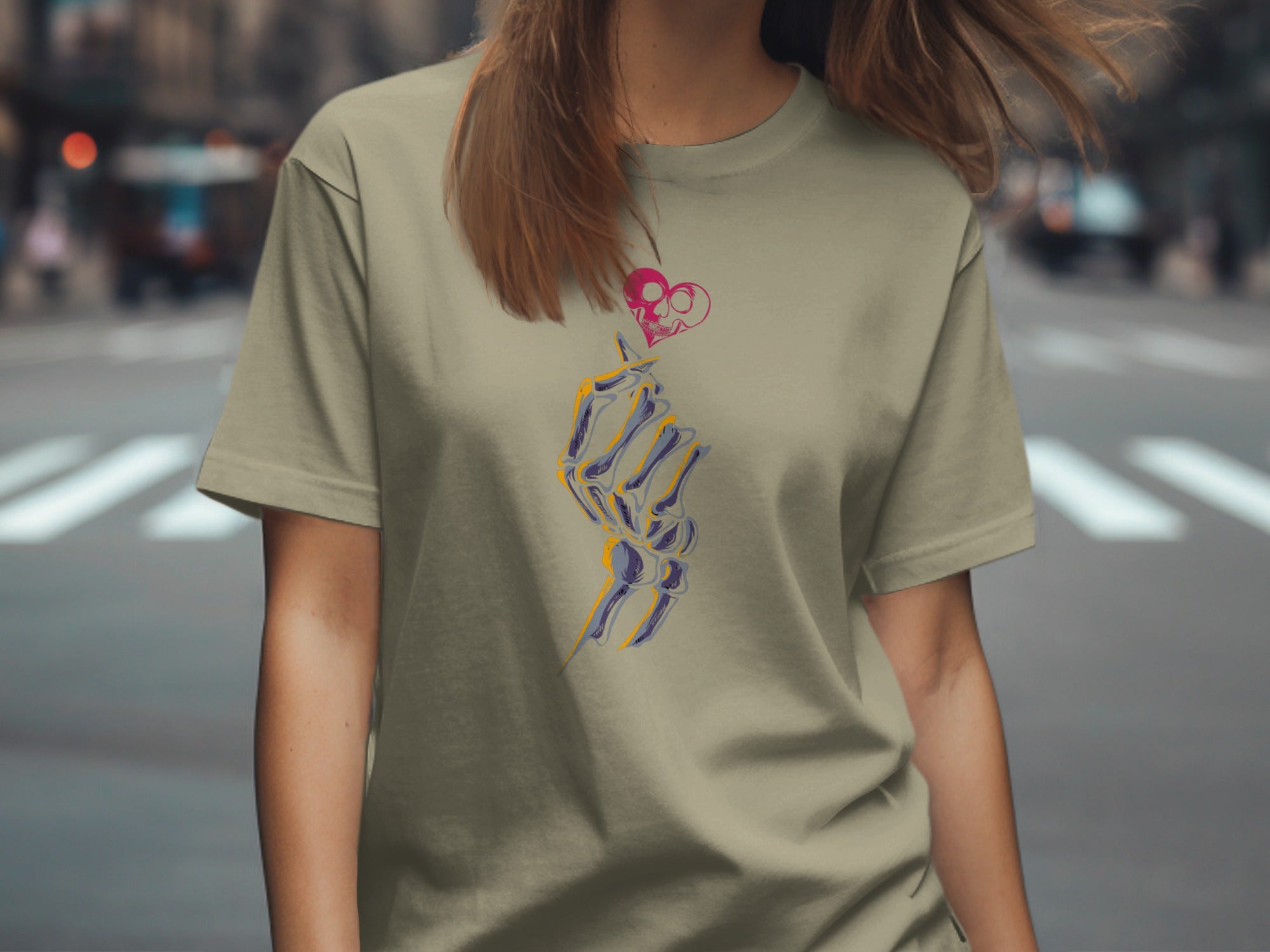 Olive t-shirt with a skeleton hand holding a pink skull heart graphic.