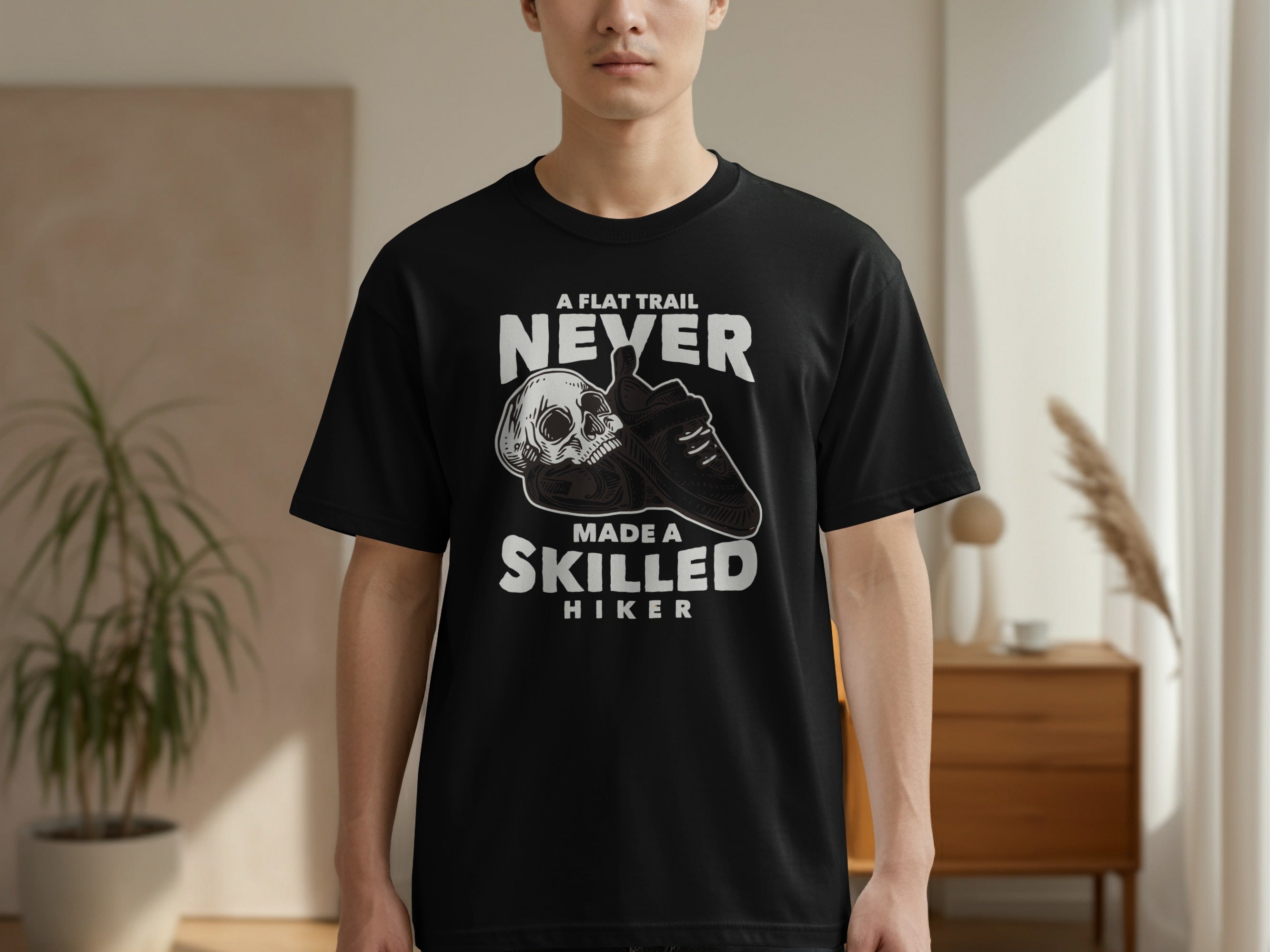 Black t-shirt with "A Flat Trail Never Made A Skilled Hiker" text and skull graphic.