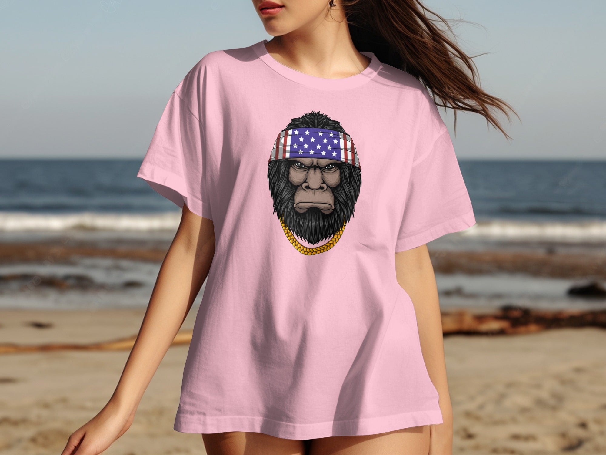 Pink t-shirt with Bigfoot graphic wearing American flag bandana and gold chain.