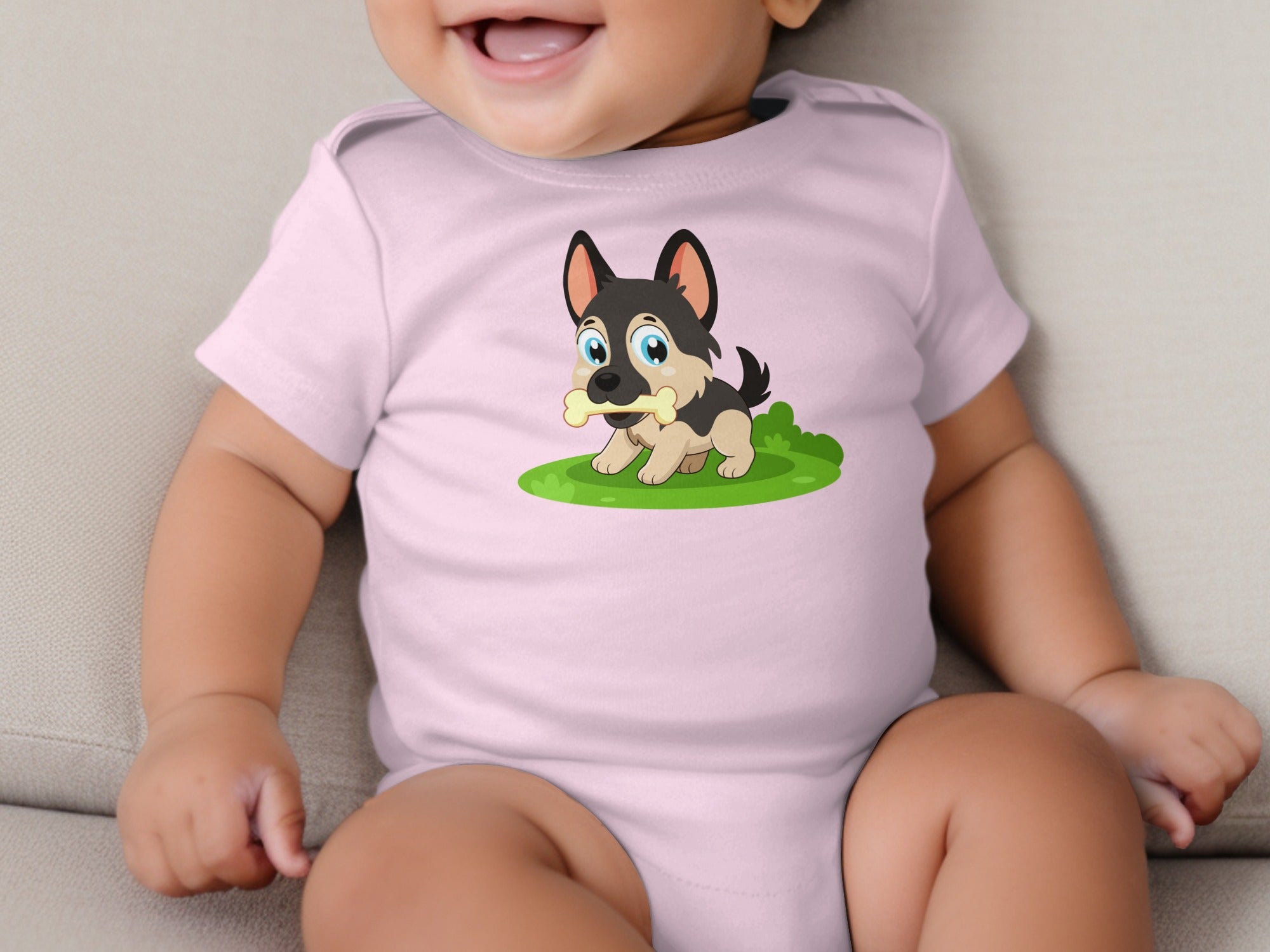 Baby in pink bodysuit with cartoon puppy holding a bone on green grass.
