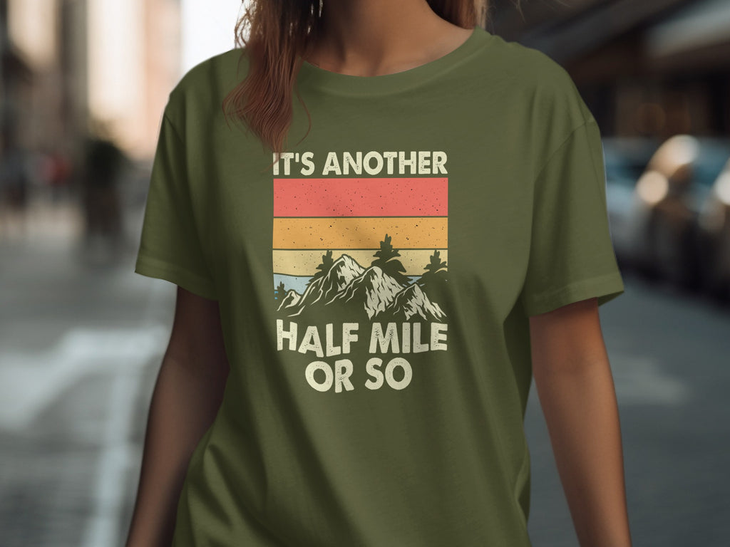 Green t-shirt with retro mountains graphic and text: IT'S ANOTHER HALF MILE OR SO.