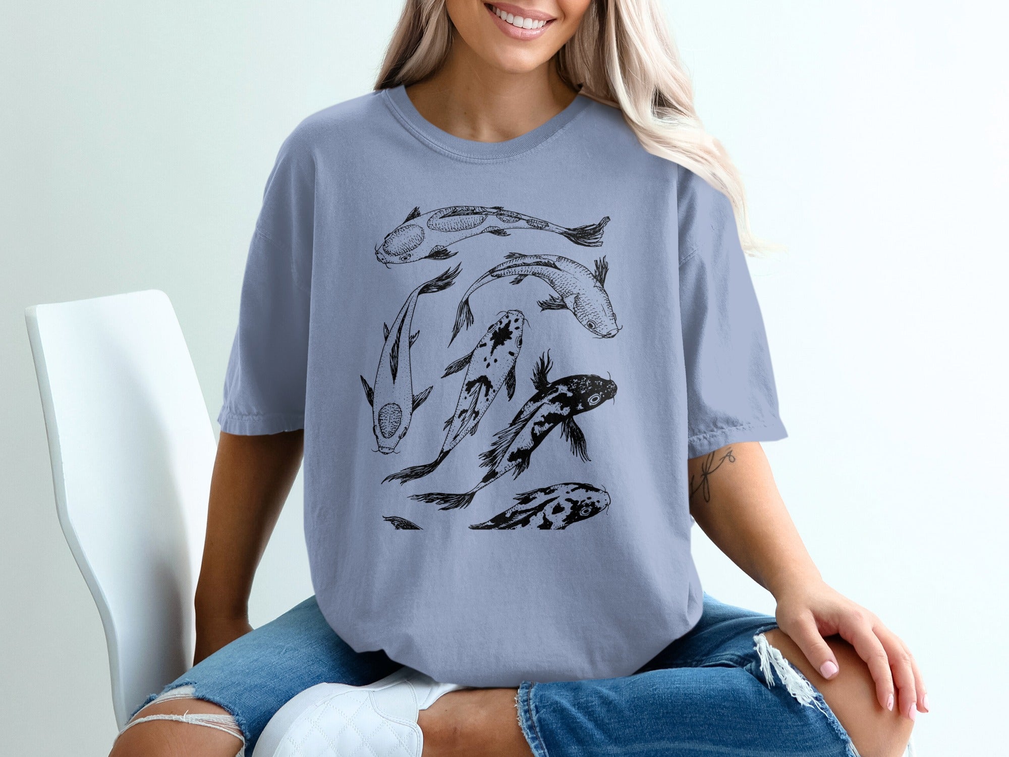 T-shirt with black line drawing of five koi fish on a light blue shirt.