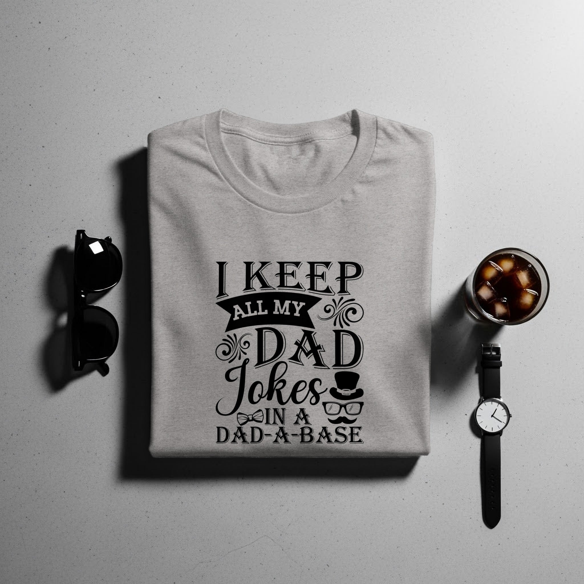 Gray t-shirt with "I Keep All My Dad Jokes in a Dad-a-base" text and icons.