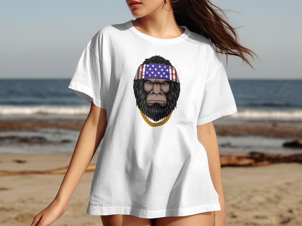 Bigfoot wearing an American flag bandana and gold chain on a white t-shirt.