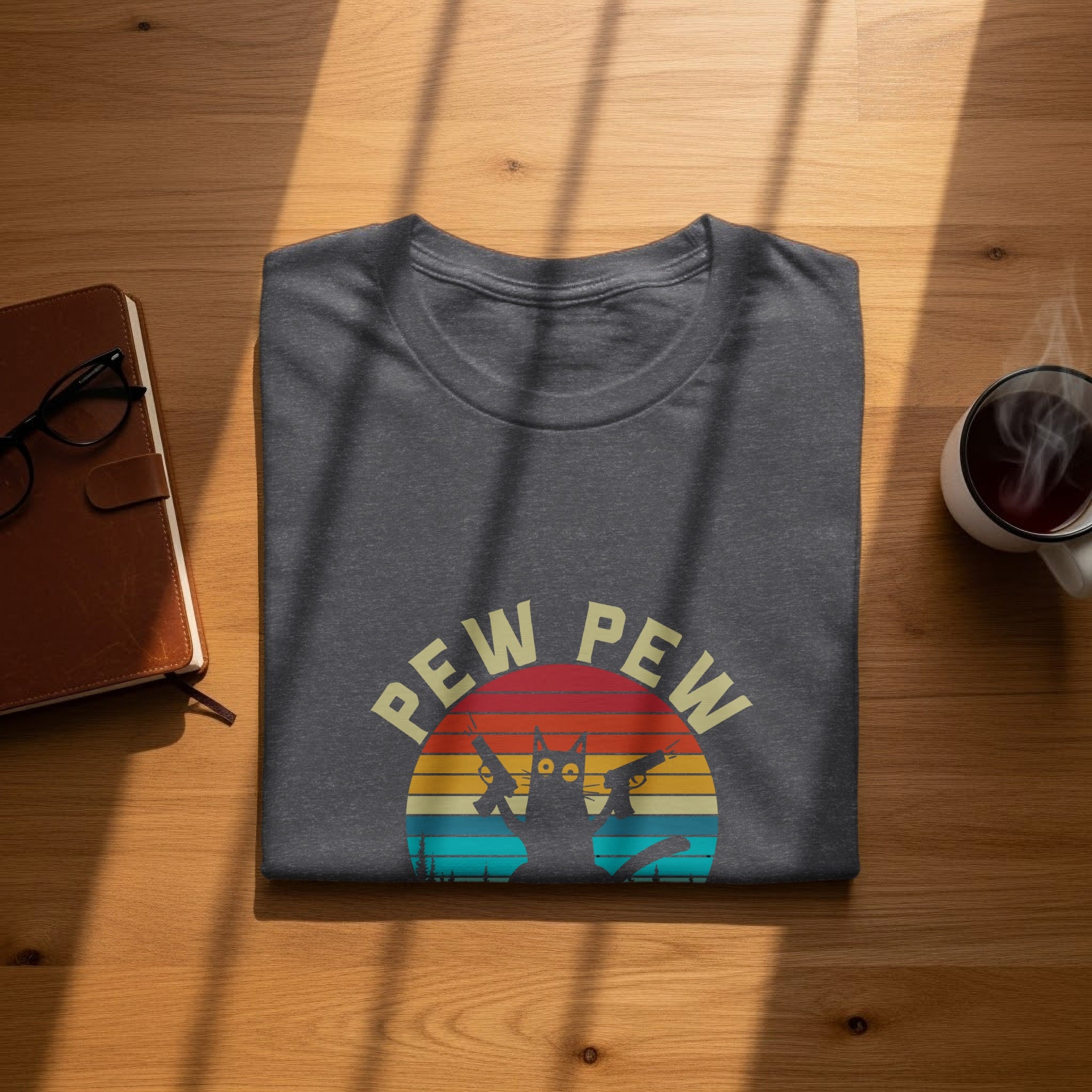 T-shirt with vintage sunset graphic of a cat holding two guns and the text "Pew Pew".