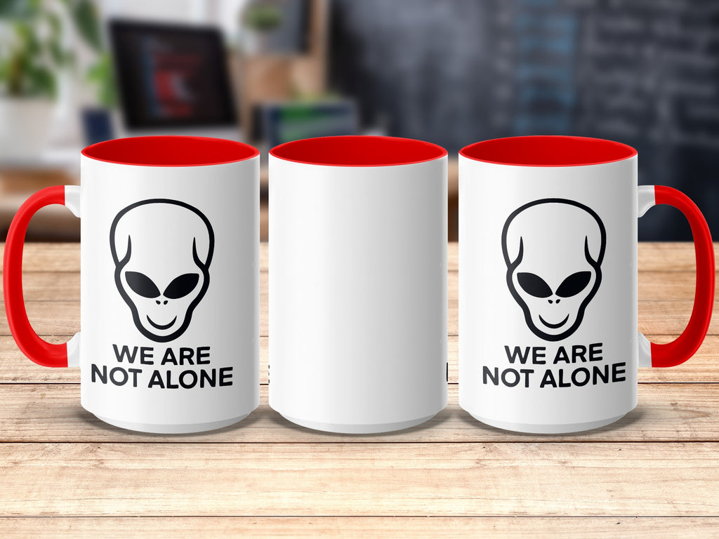 White mug with alien graphic and text "WE ARE NOT ALONE" on the side.