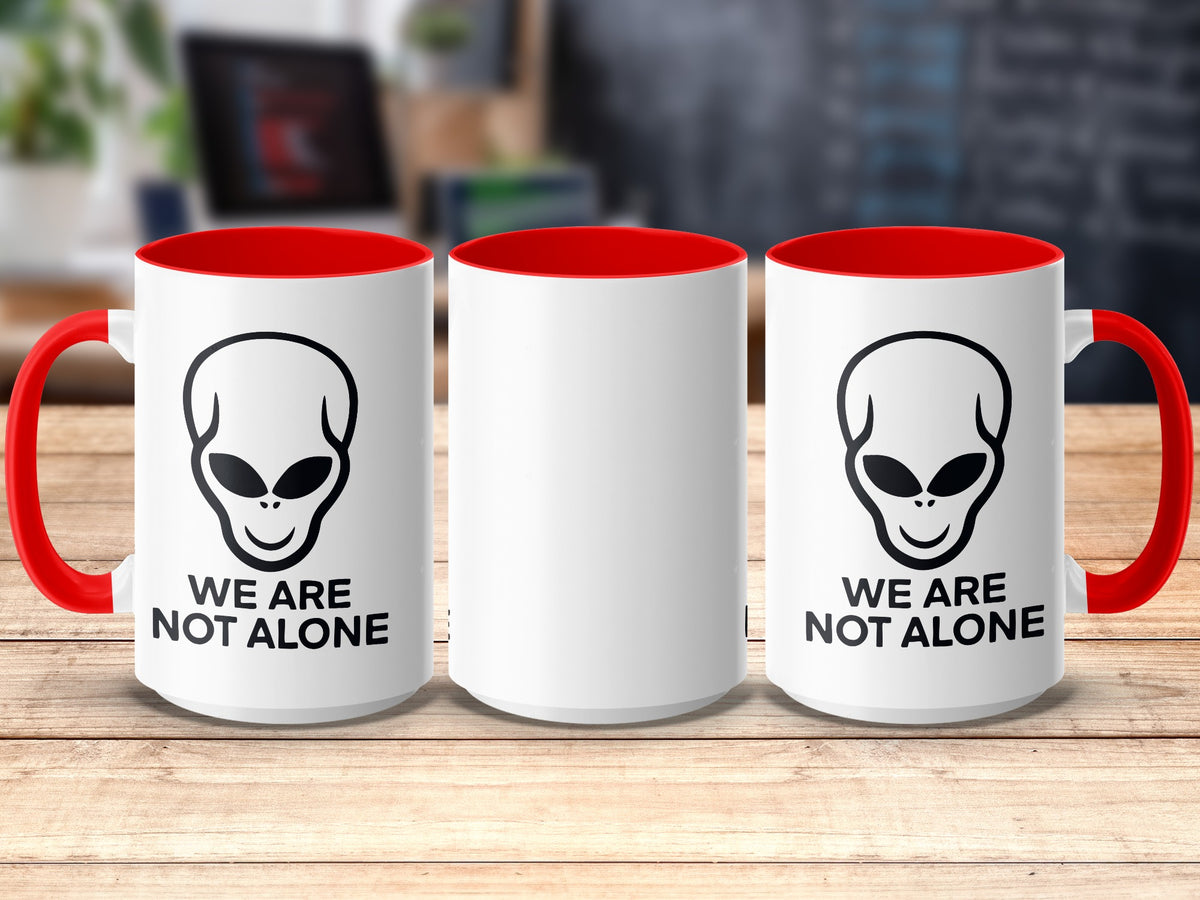 White mug with alien graphic and text "WE ARE NOT ALONE" on the side.