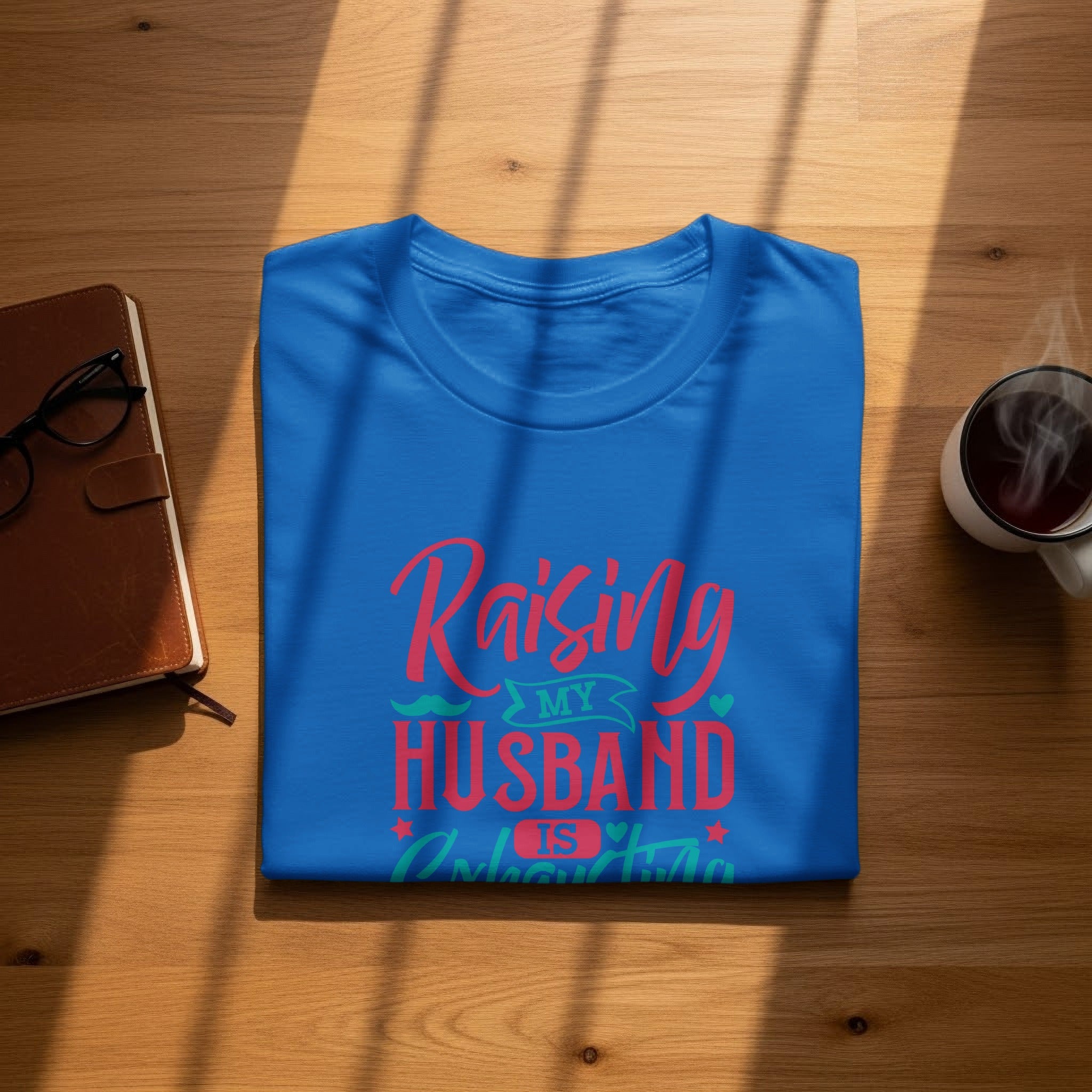 Blue t-shirt with "Raising My Husband Is An Adventure" text in red and teal.