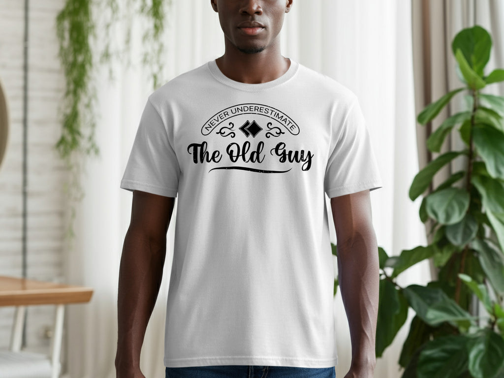 White t-shirt with "NEVER UNDERESTIMATE The Old Guy" text in black lettering.