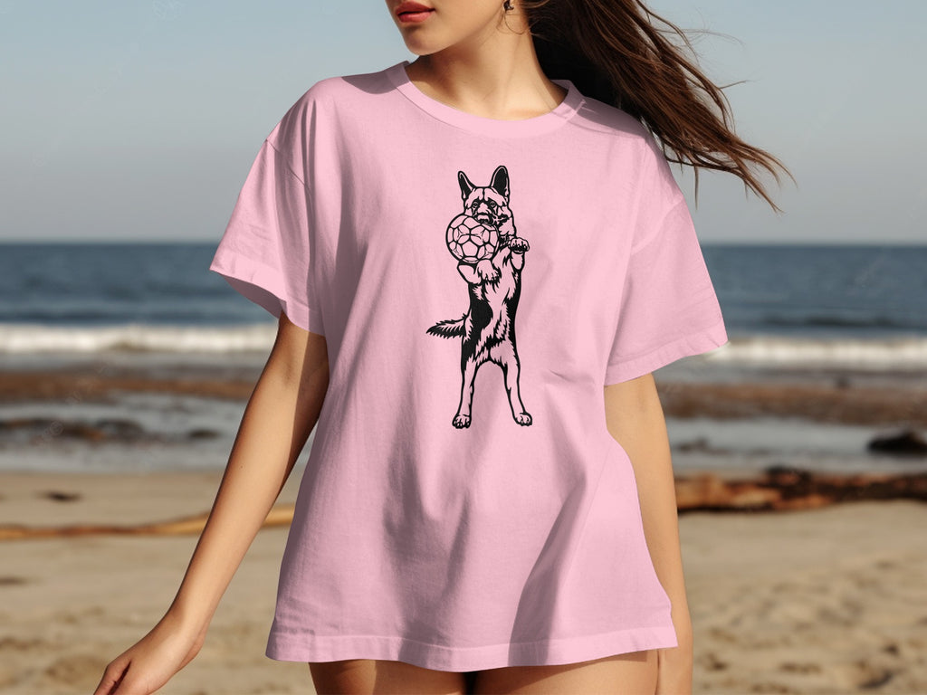 Pink t-shirt with black outline graphic of a German Shepherd holding a soccer ball.