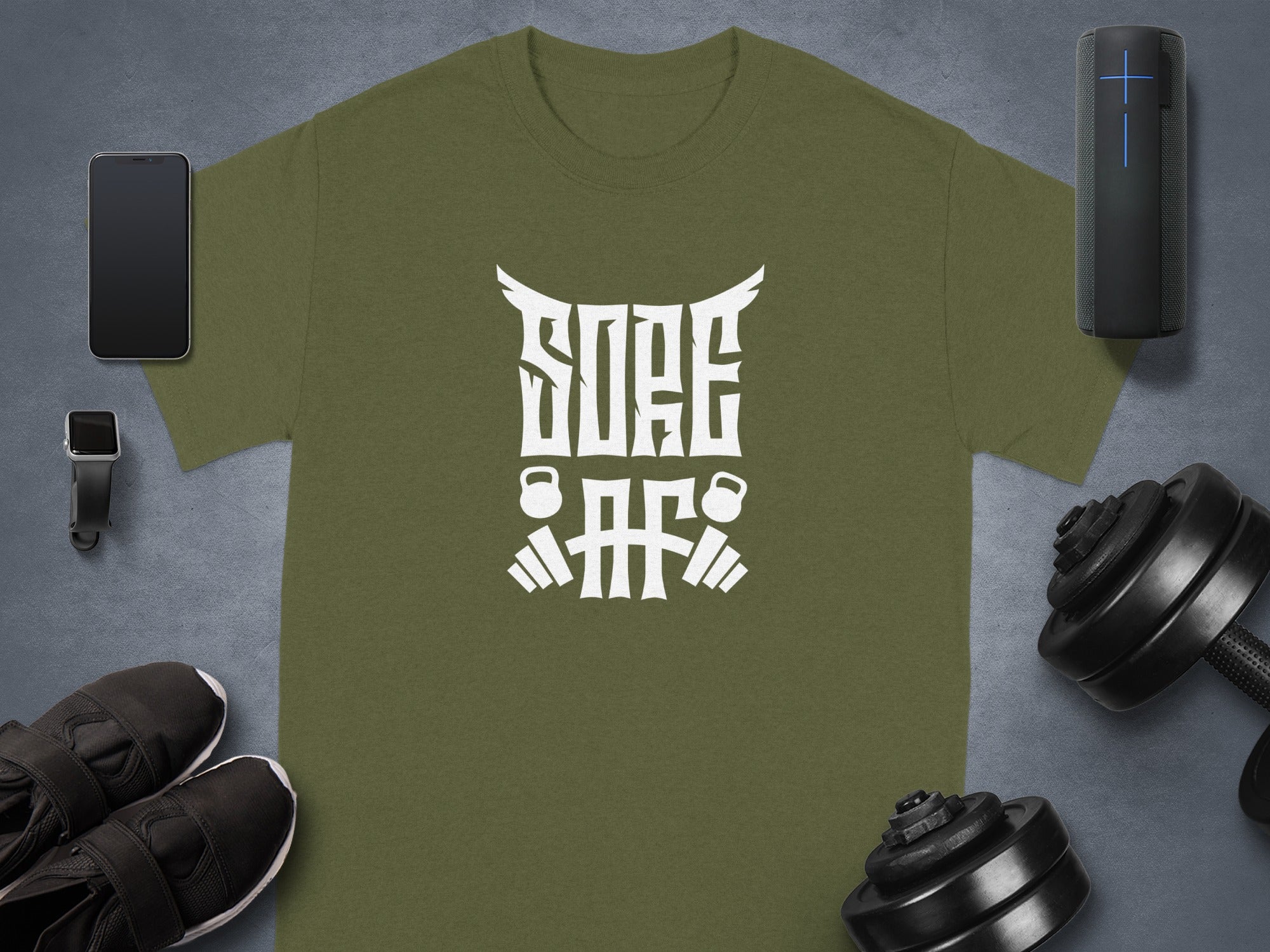 Olive green t-shirt with white text and gym graphics, surrounded by workout gear.
