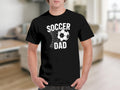 Black t-shirt with white text "SOCCER DAD" and soccer ball in net graphic