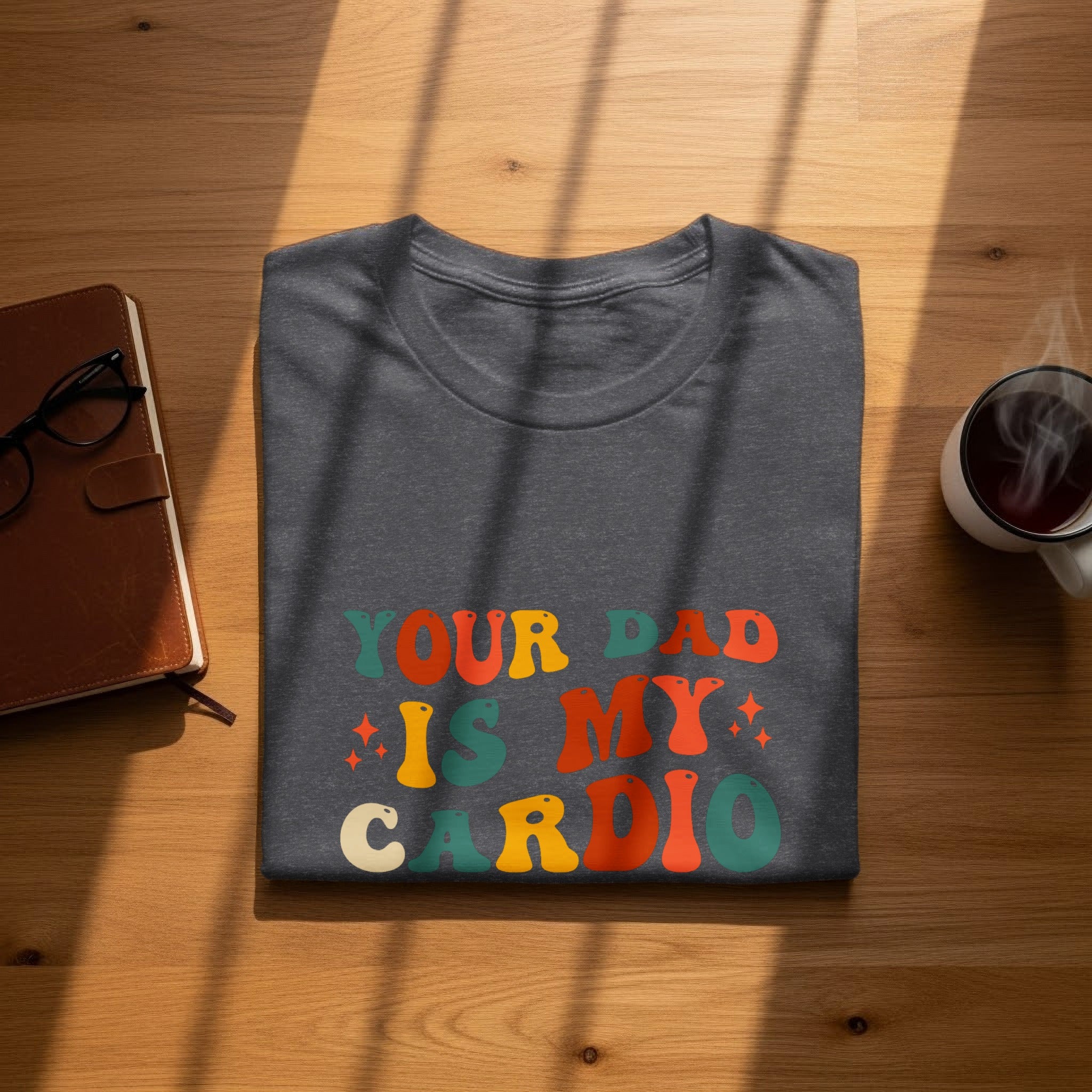 Dark grey t-shirt with "YOUR DAD IS MY CARDIO" text in retro font.